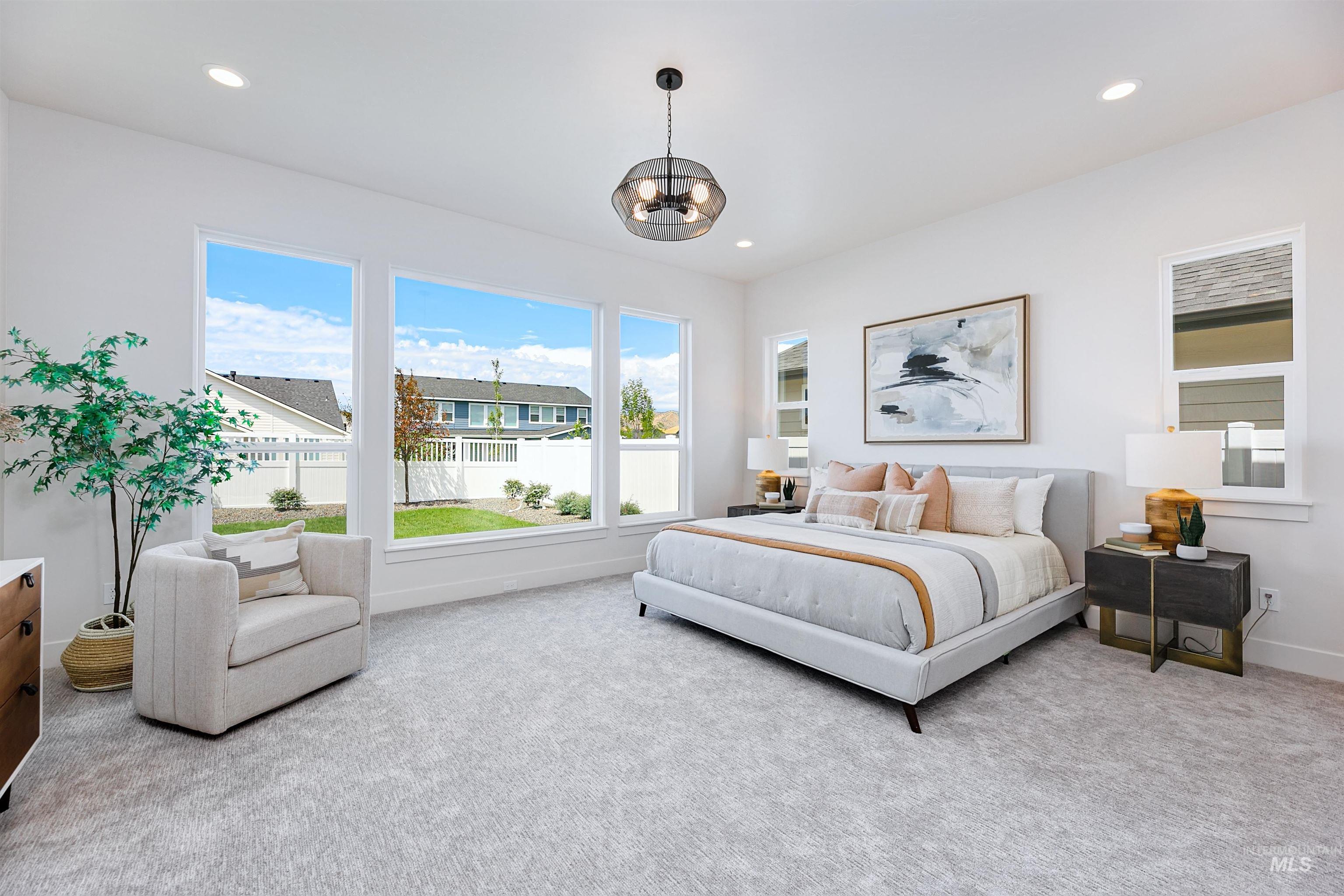 Spacious bedroom featuring multiple large windows, recessed lighting, a contemporary chandelier, and light-toned carpeting