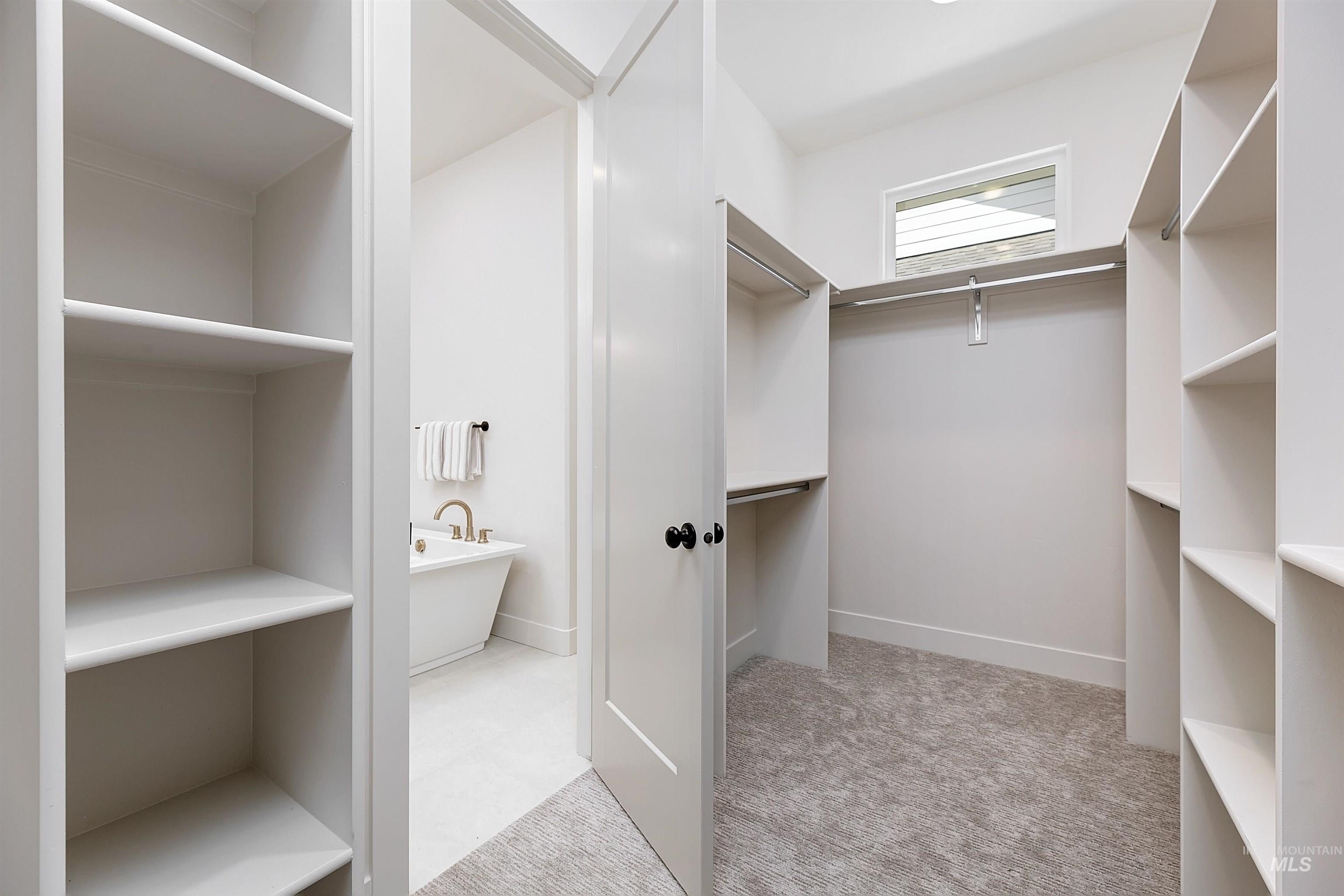 Walk-in closet with carpet flooring, built-in shelving, and hanging rods