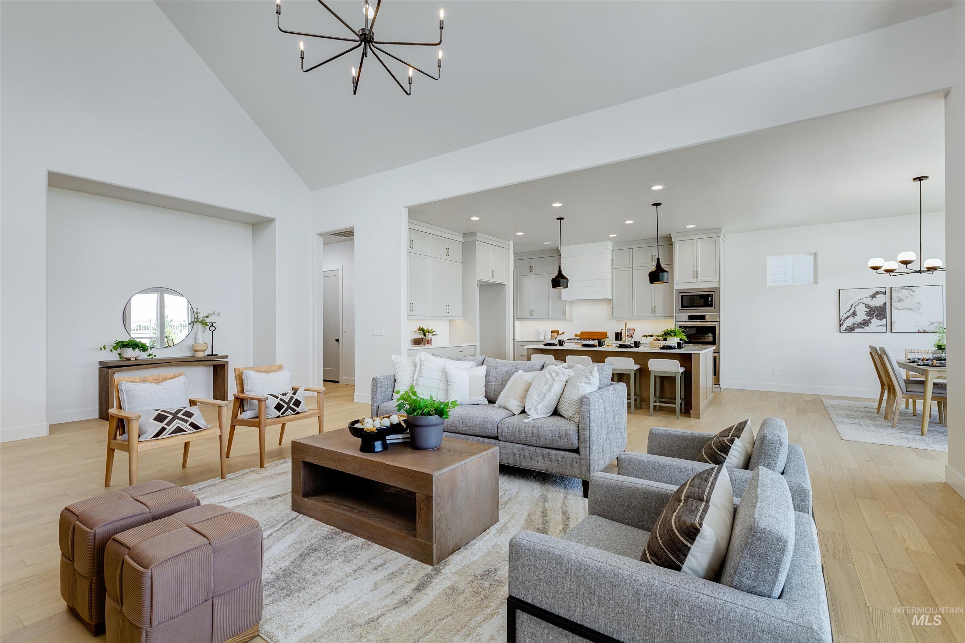 Spacious great room featuring vaulted ceilings, light wood-finish flooring, and a contemporary chandelier