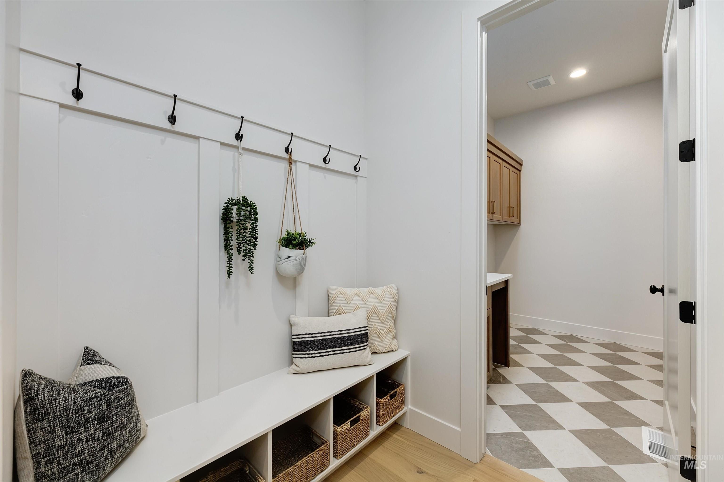 Entryway mudroom featuring board and batten paneling, a built-in bench with cubby storage, and multiple coat hooks