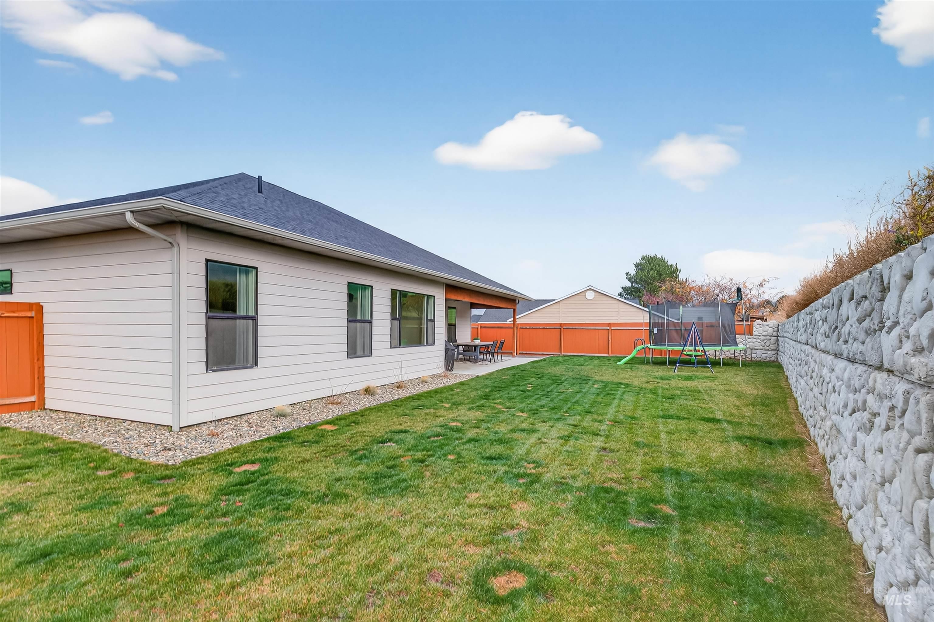 Fenced backyard with a trampoline and a patio