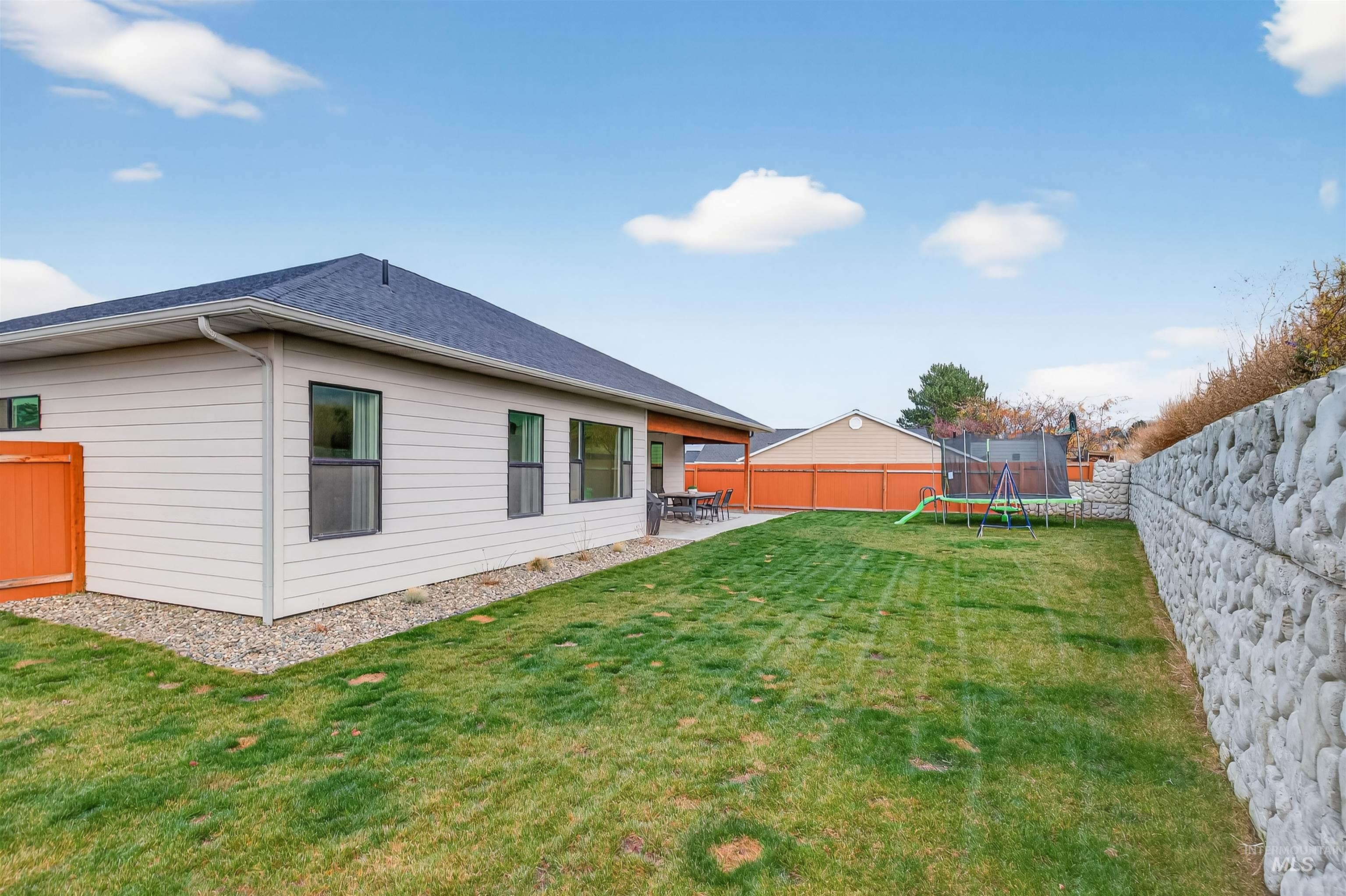 Rear view of property featuring a trampoline, a patio area, a fenced backyard, and a shingled roof