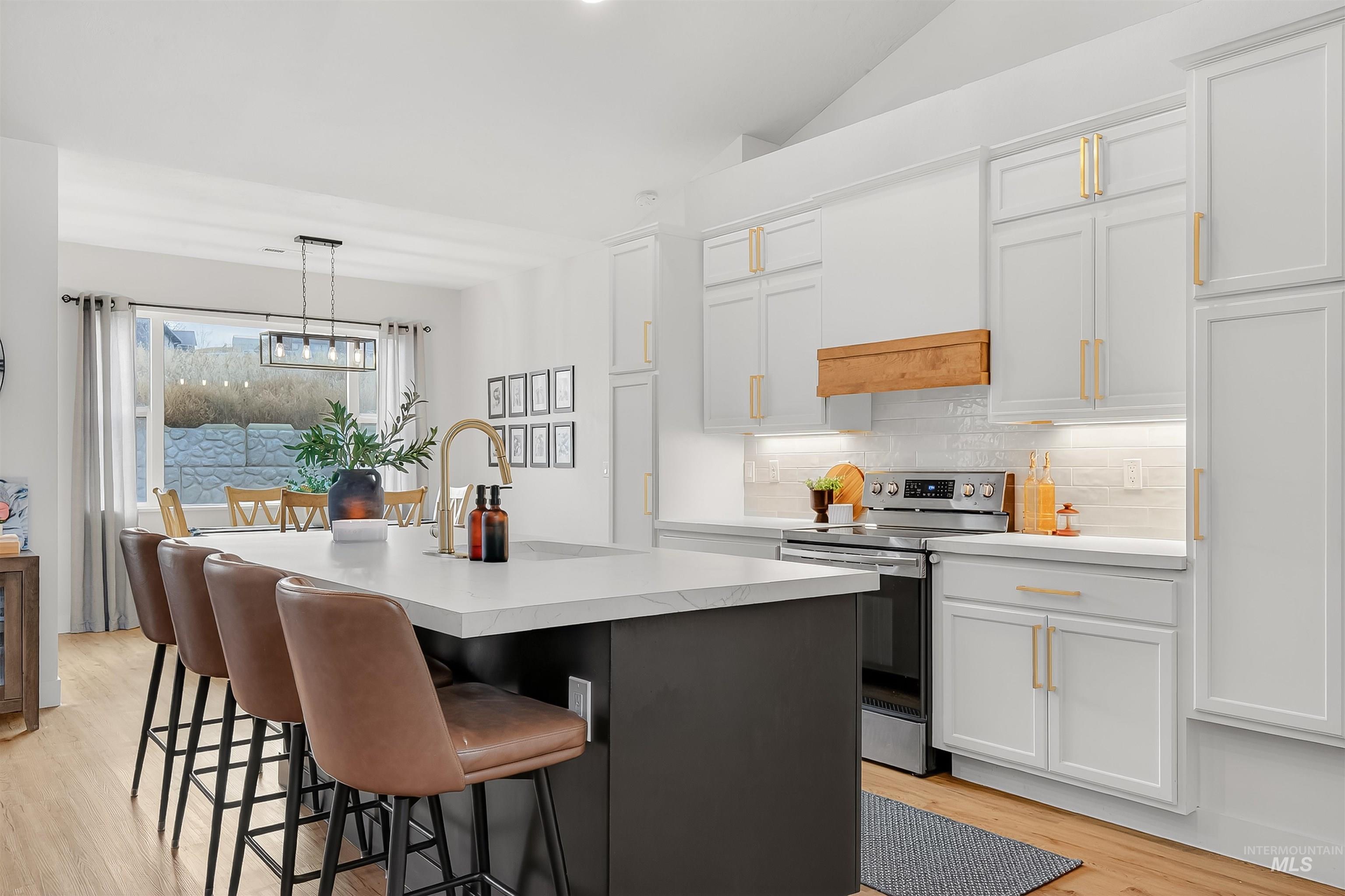 Kitchen featuring electric stove, tasteful backsplash, light countertops, decorative light fixtures, and white cabinetry