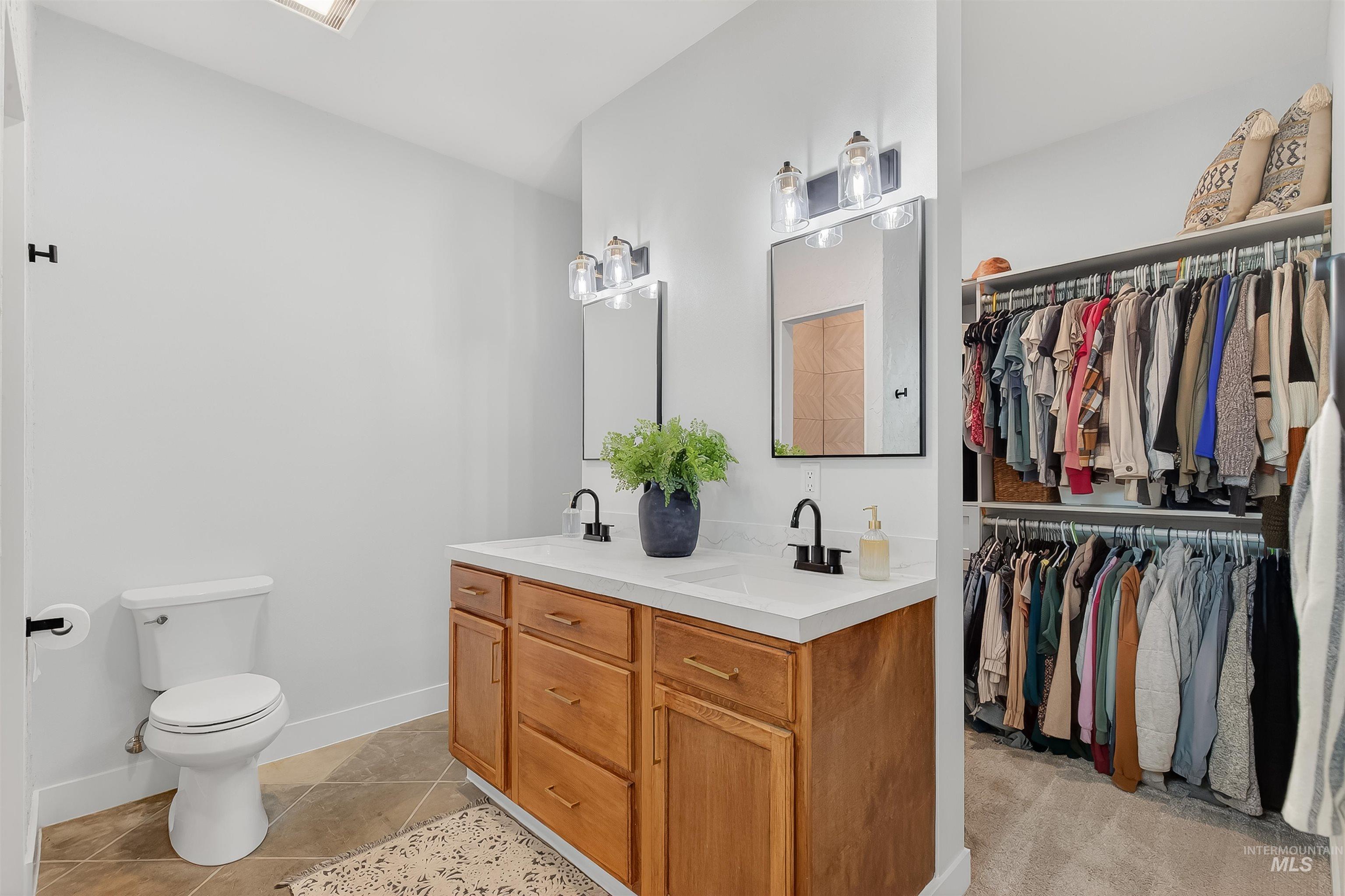 Bathroom featuring double vanity, a walk in closet, and light tile patterned floors