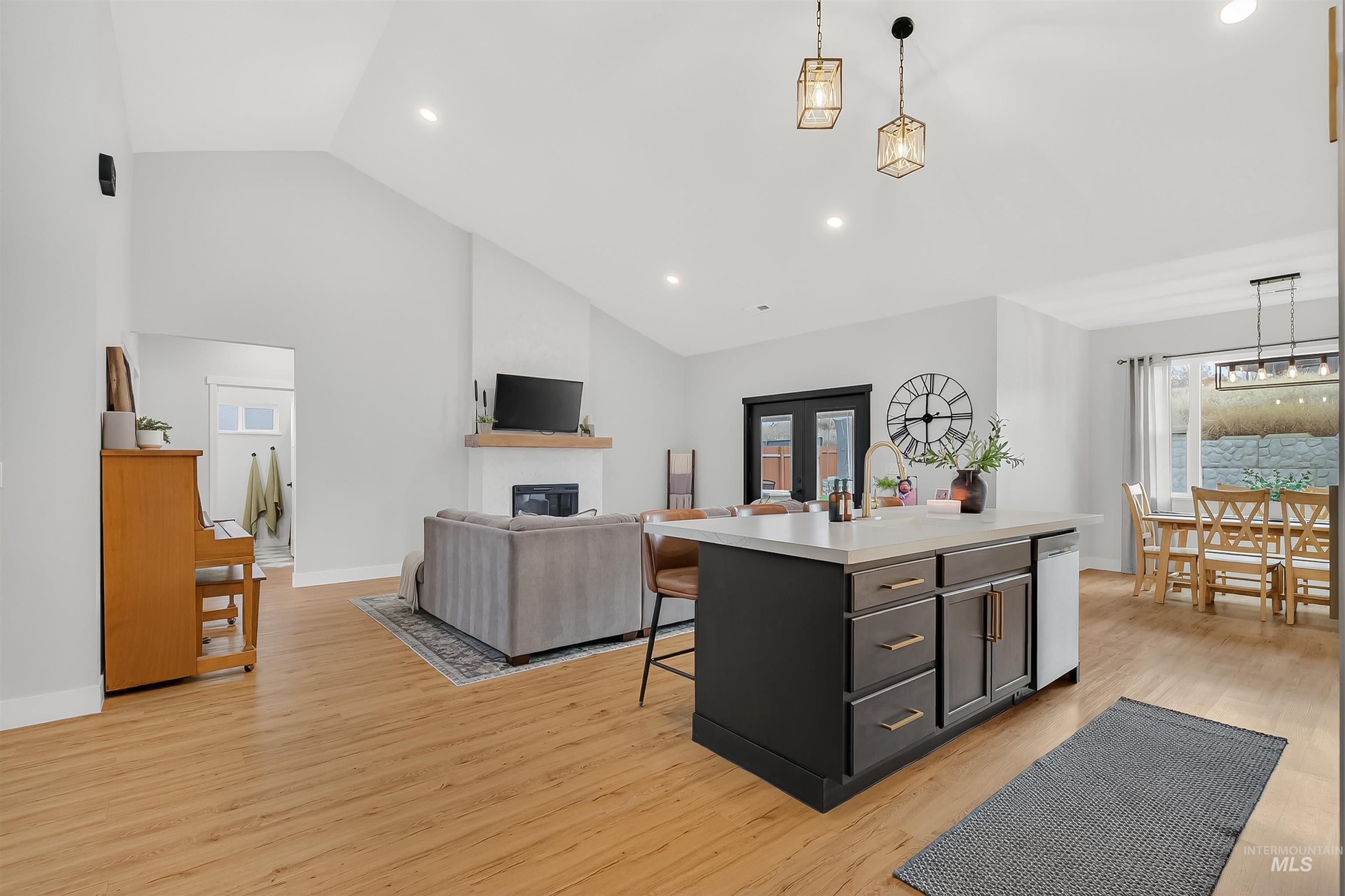 Kitchen with decorative light fixtures, light countertops, a kitchen island with sink, a kitchen bar, and recessed lighting