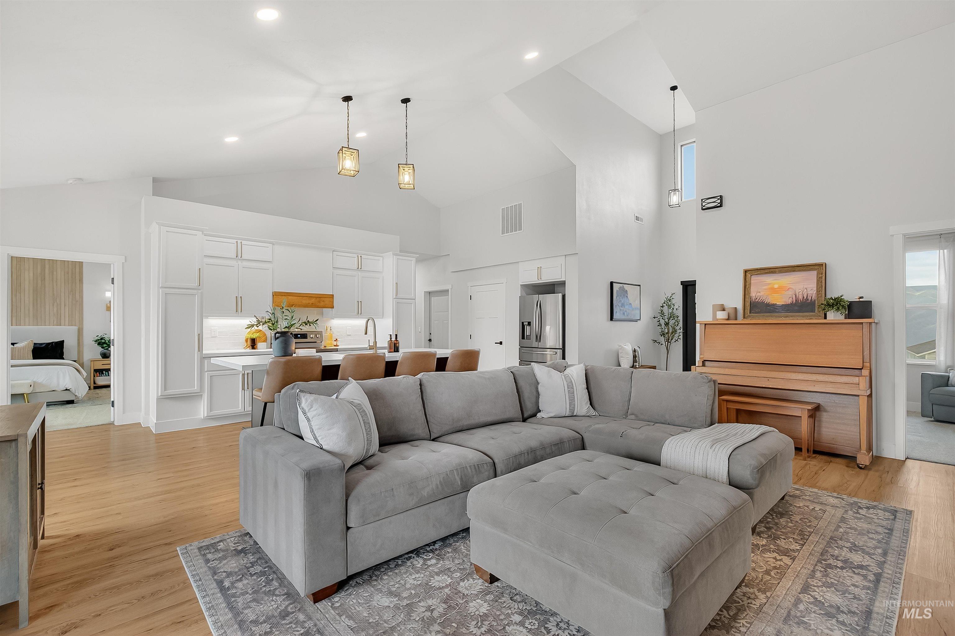 Living area featuring high vaulted ceiling and light wood-style floors