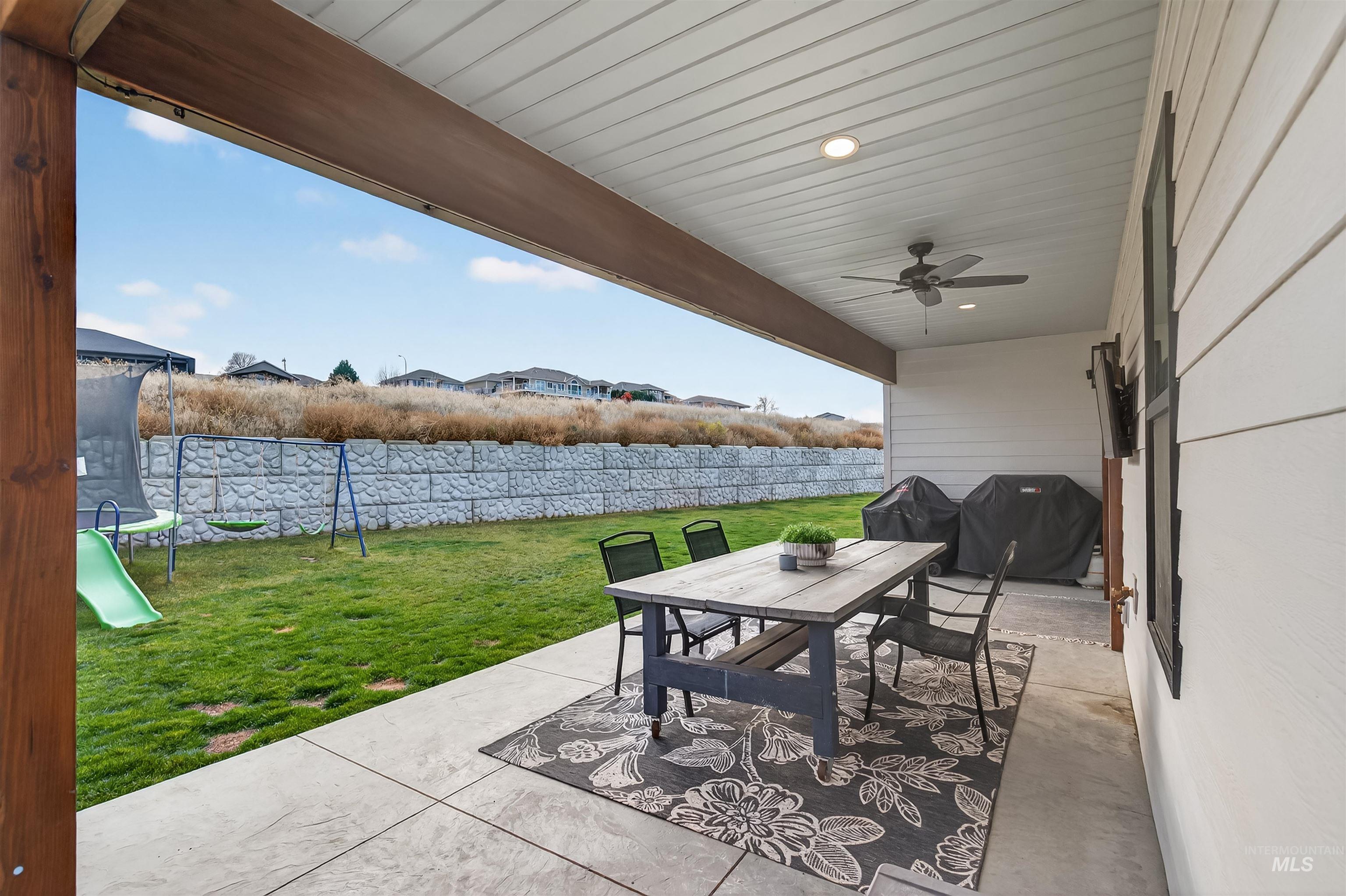 Fenced backyard featuring outdoor dining space, a patio, a ceiling fan, and grilling area