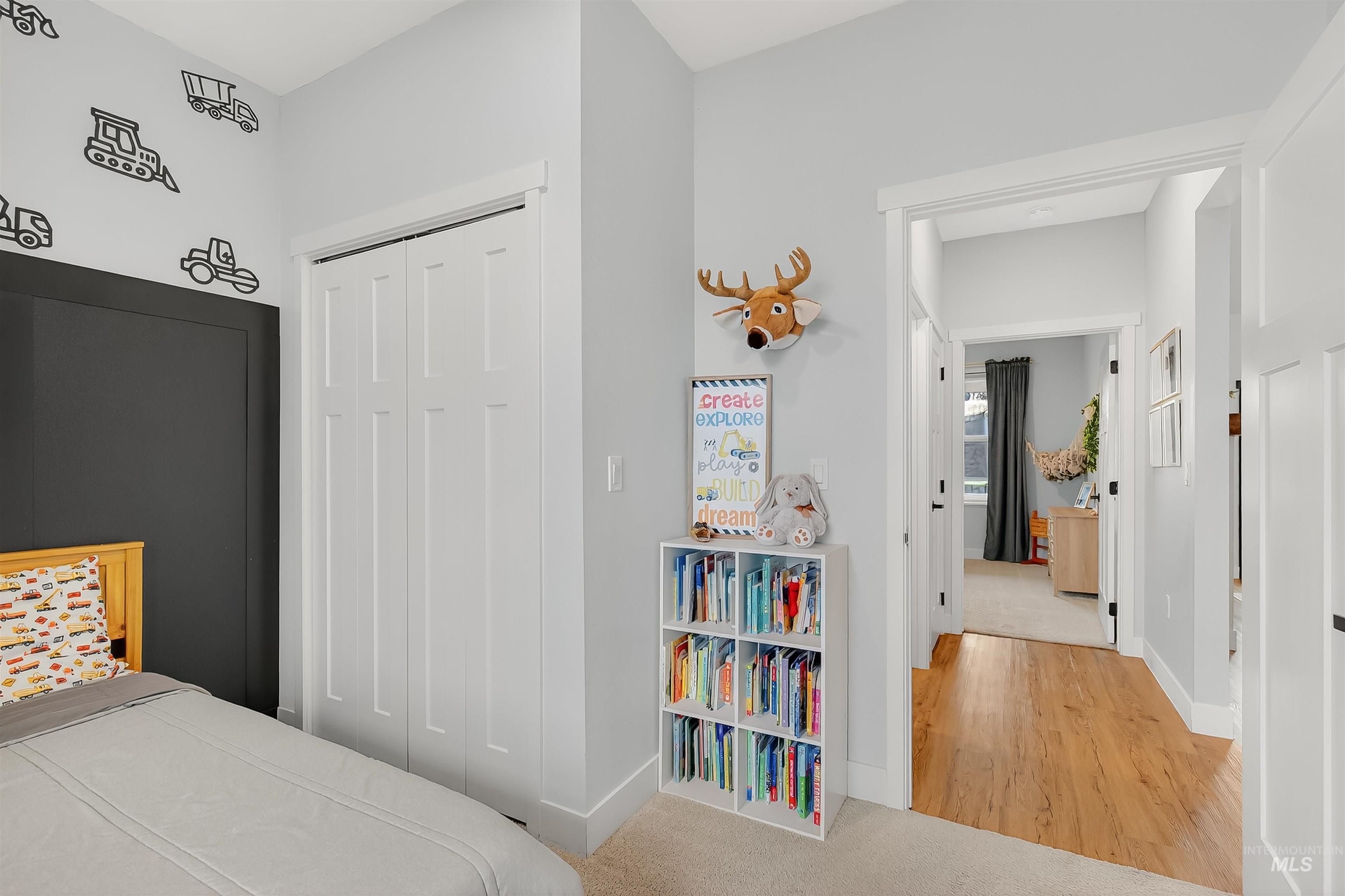 Carpeted bedroom with a closet and wood finished floors