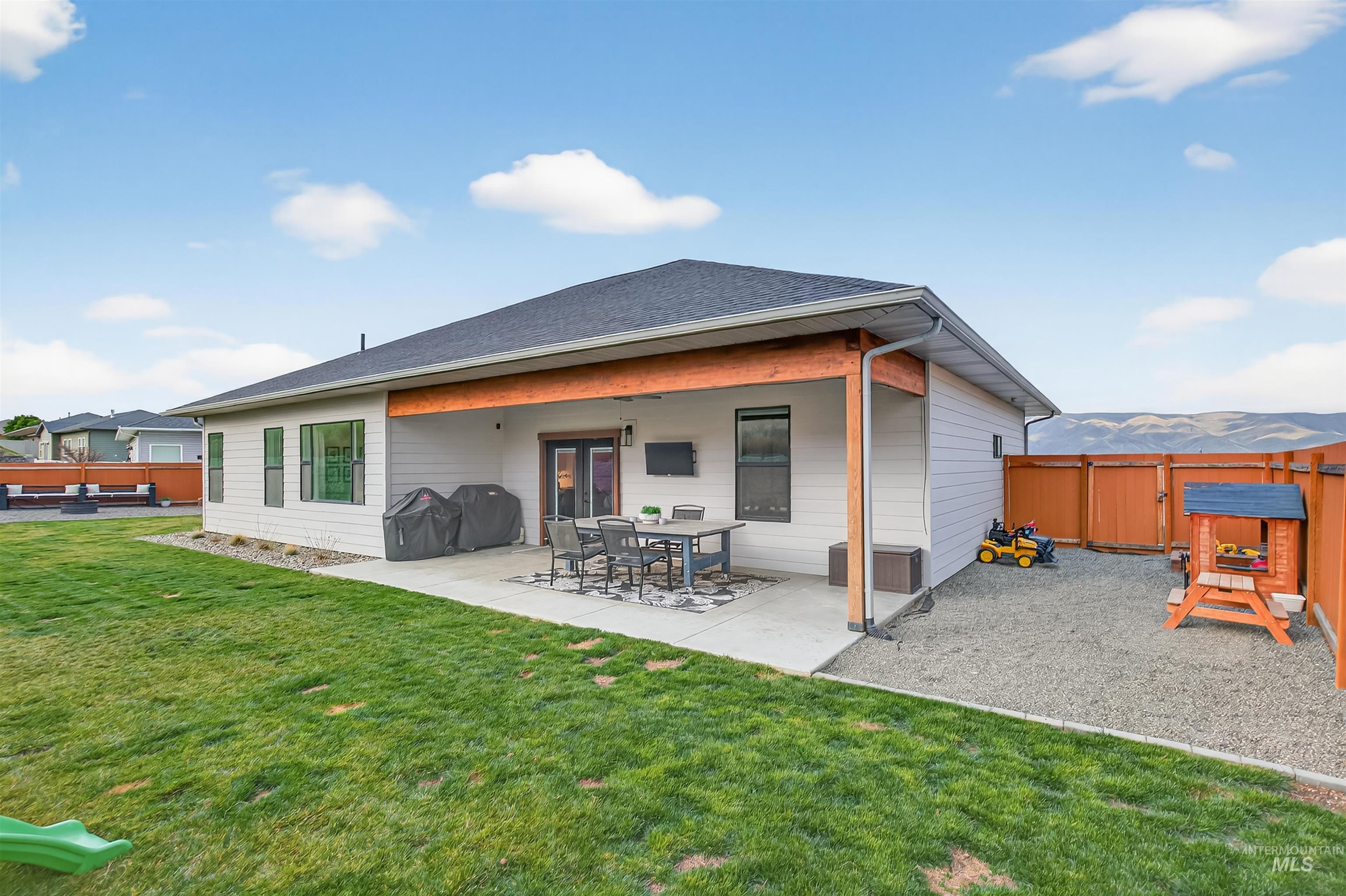 Back of house featuring a patio, a mountain view, and a shingled roof