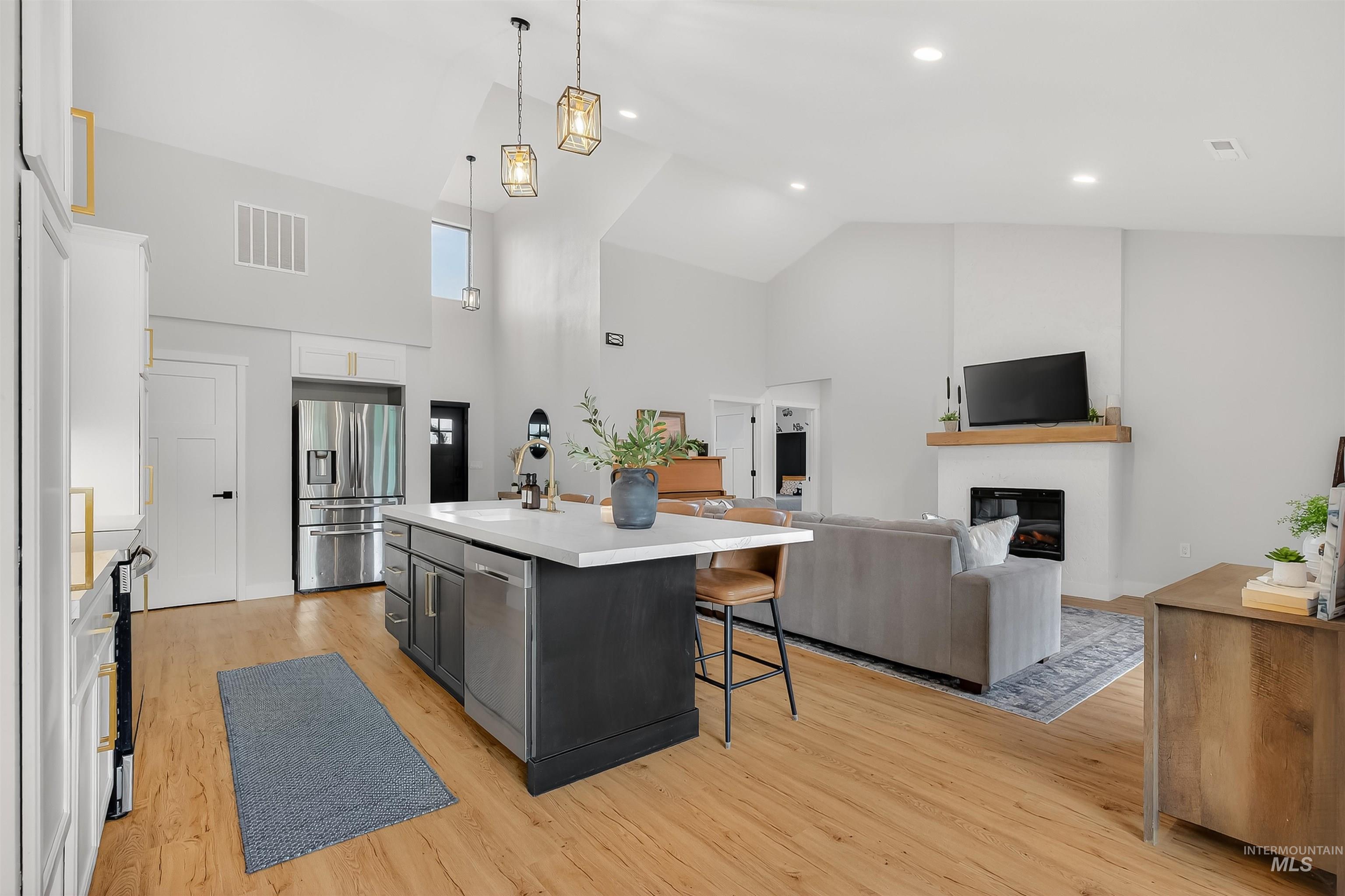 Kitchen featuring a kitchen bar, hanging light fixtures, light countertops, an island with sink, and appliances with stainless steel finishes