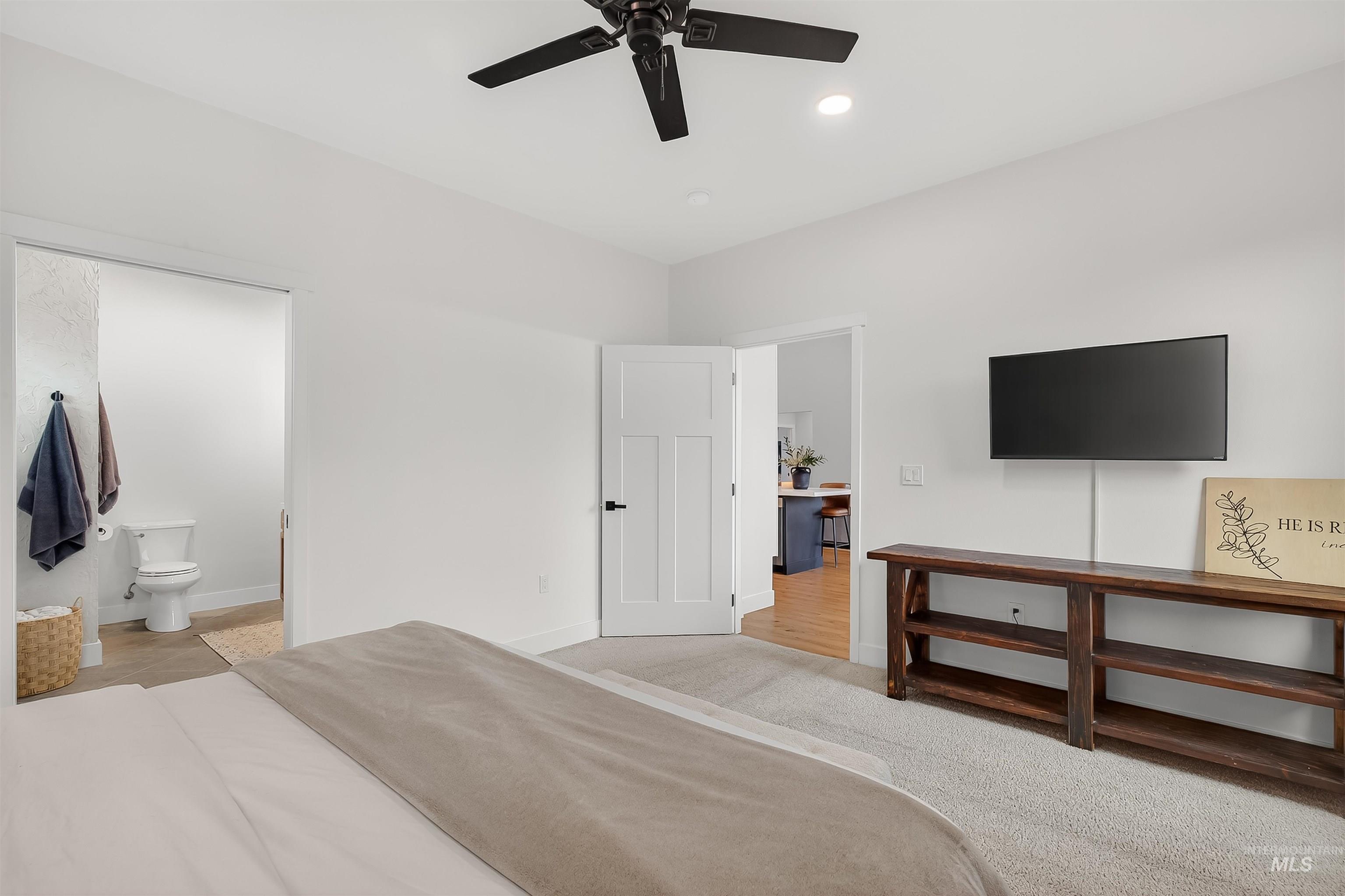 Carpeted bedroom with a ceiling fan and ensuite bathroom