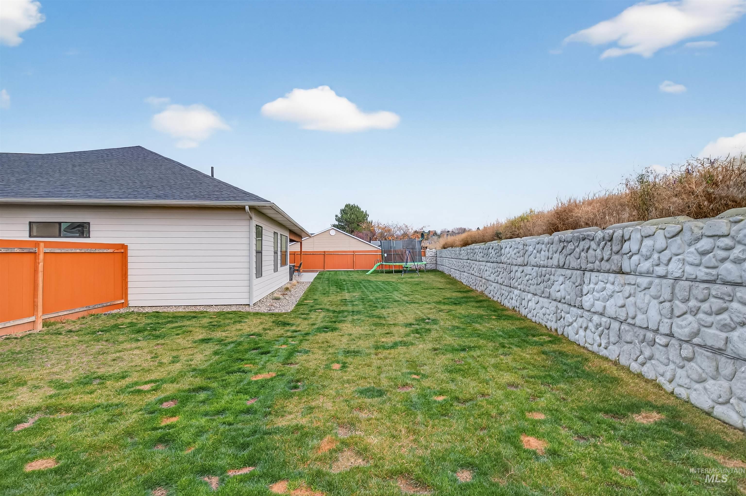 Fenced backyard featuring a trampoline