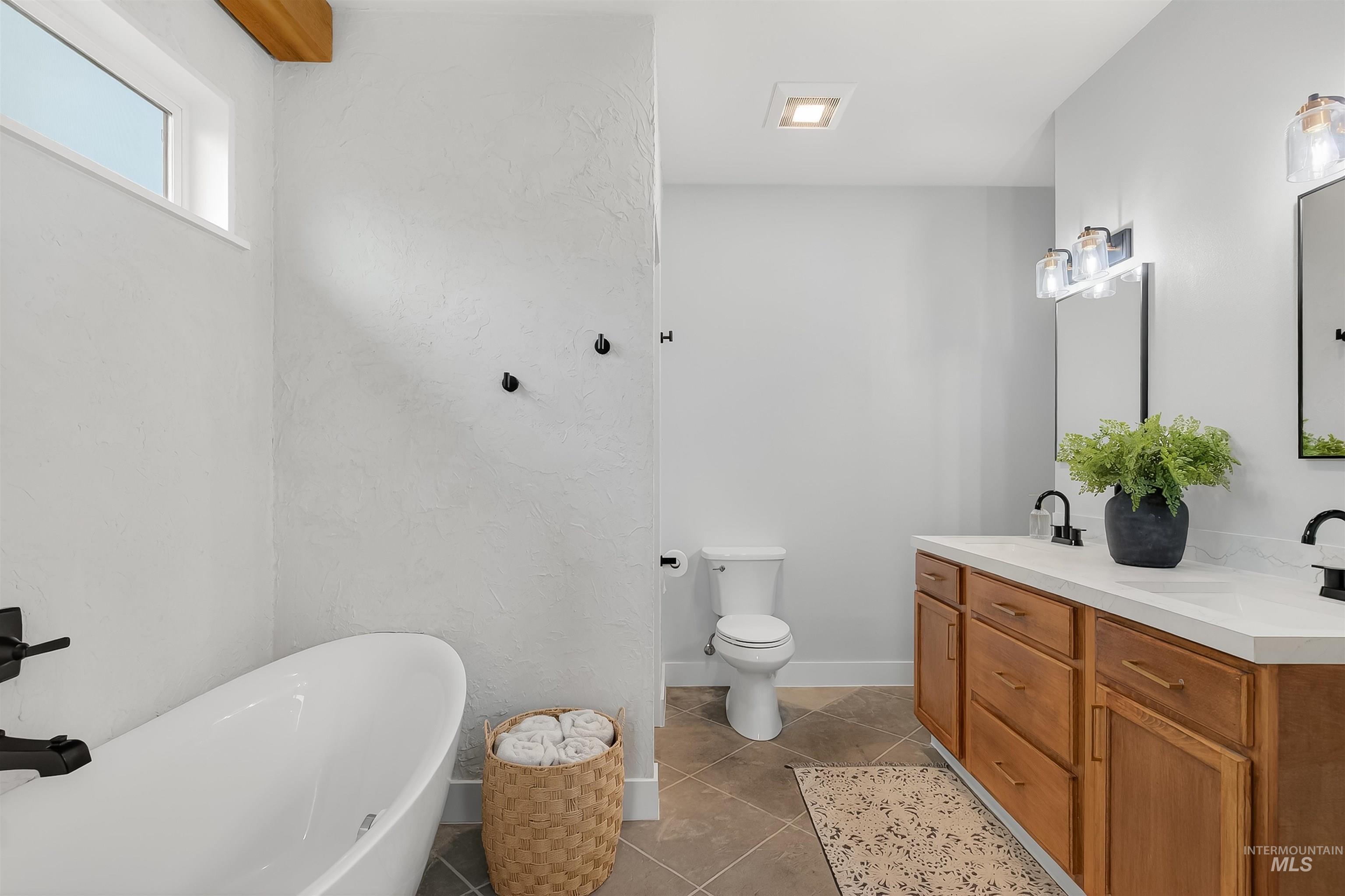 Full bathroom with double vanity, a freestanding tub, and light tile patterned floors