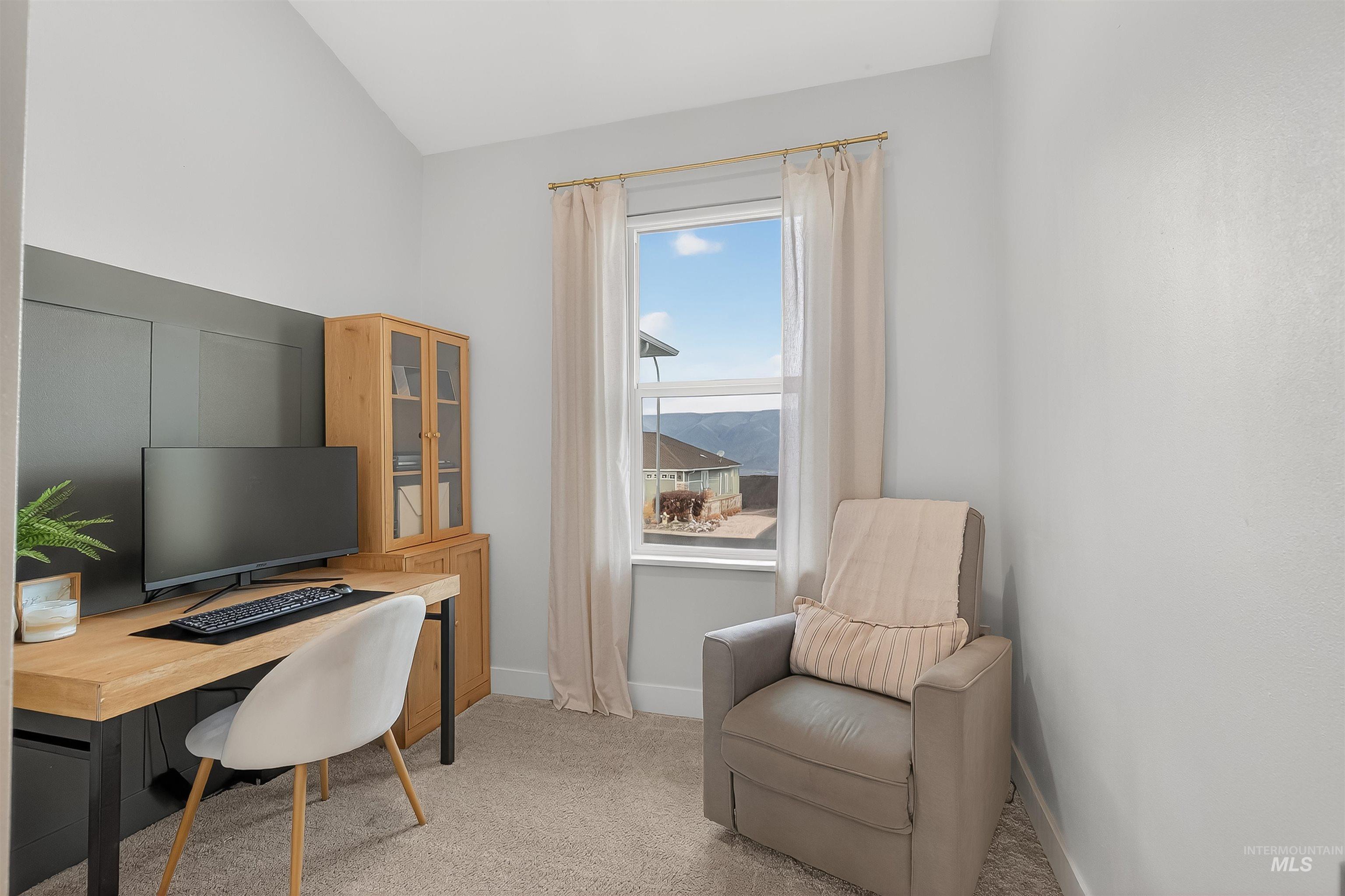 Home office with light carpet and vaulted ceiling