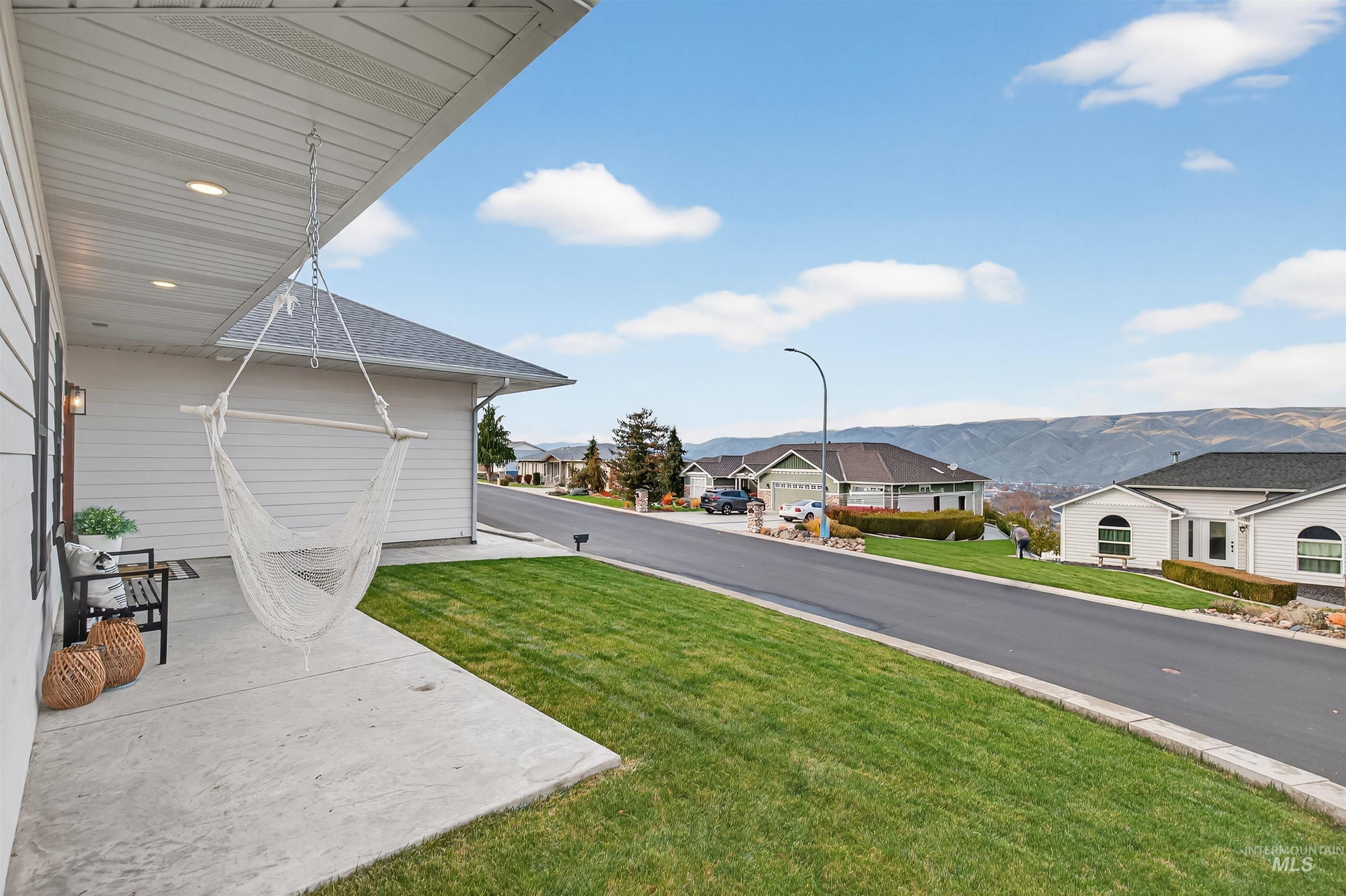 View of green lawn with a patio area, a mountain view, and a residential view