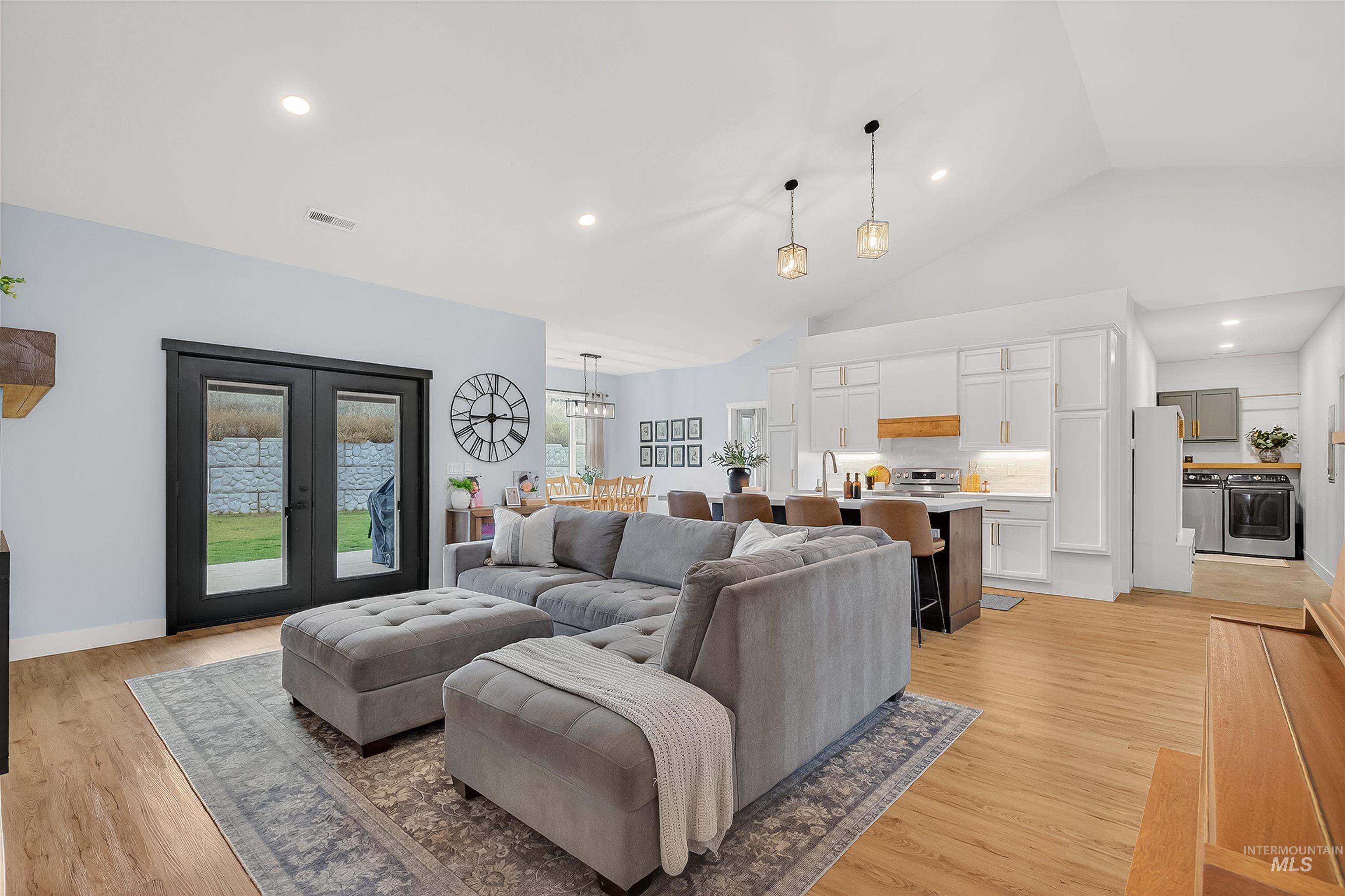 Living area featuring light wood finished floors, recessed lighting, washing machine and dryer, high vaulted ceiling, and french doors