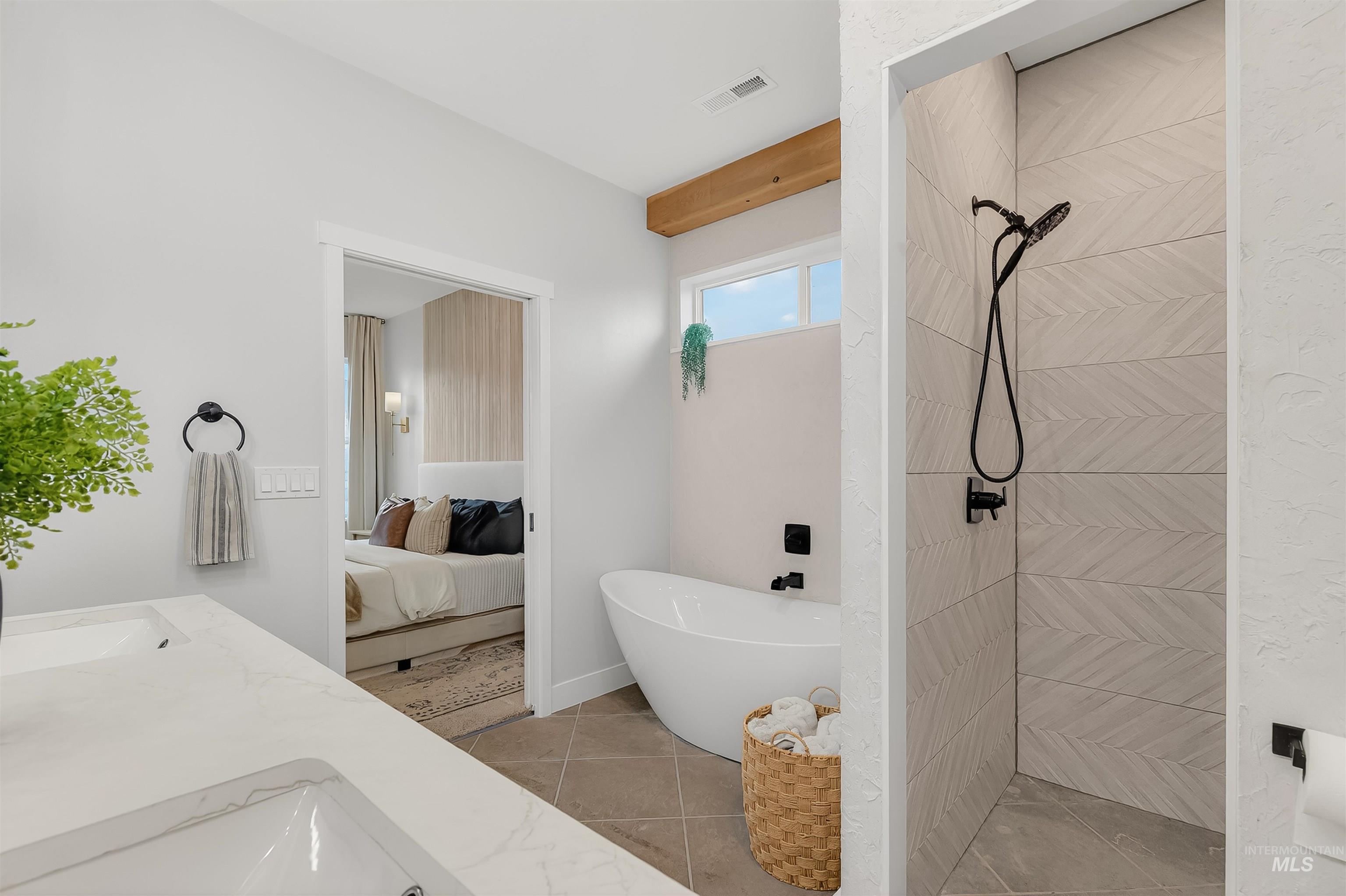 Full bathroom with ensuite bath, a freestanding bath, a tile shower, and double vanity
