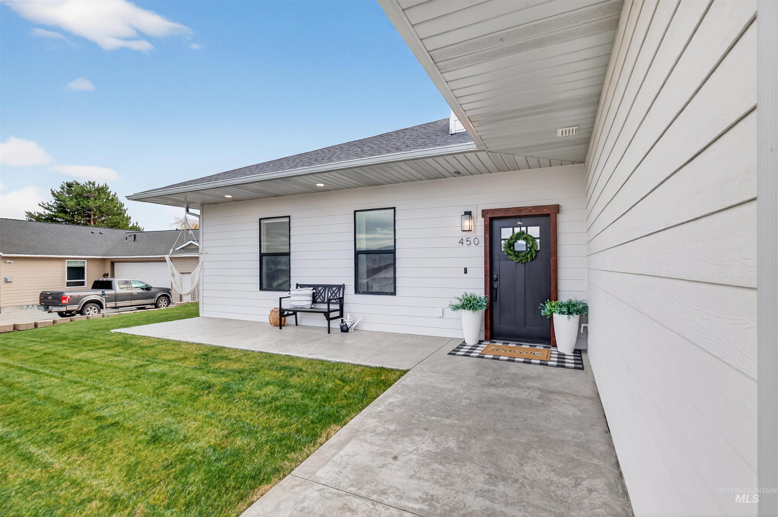 View of exterior entry featuring a yard and a shingled roof