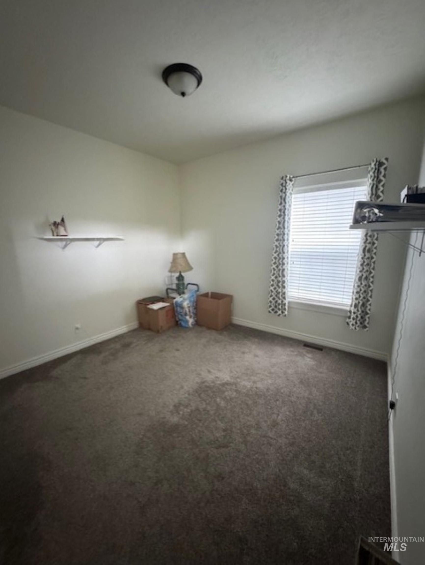 Empty room with dark colored carpet and baseboards