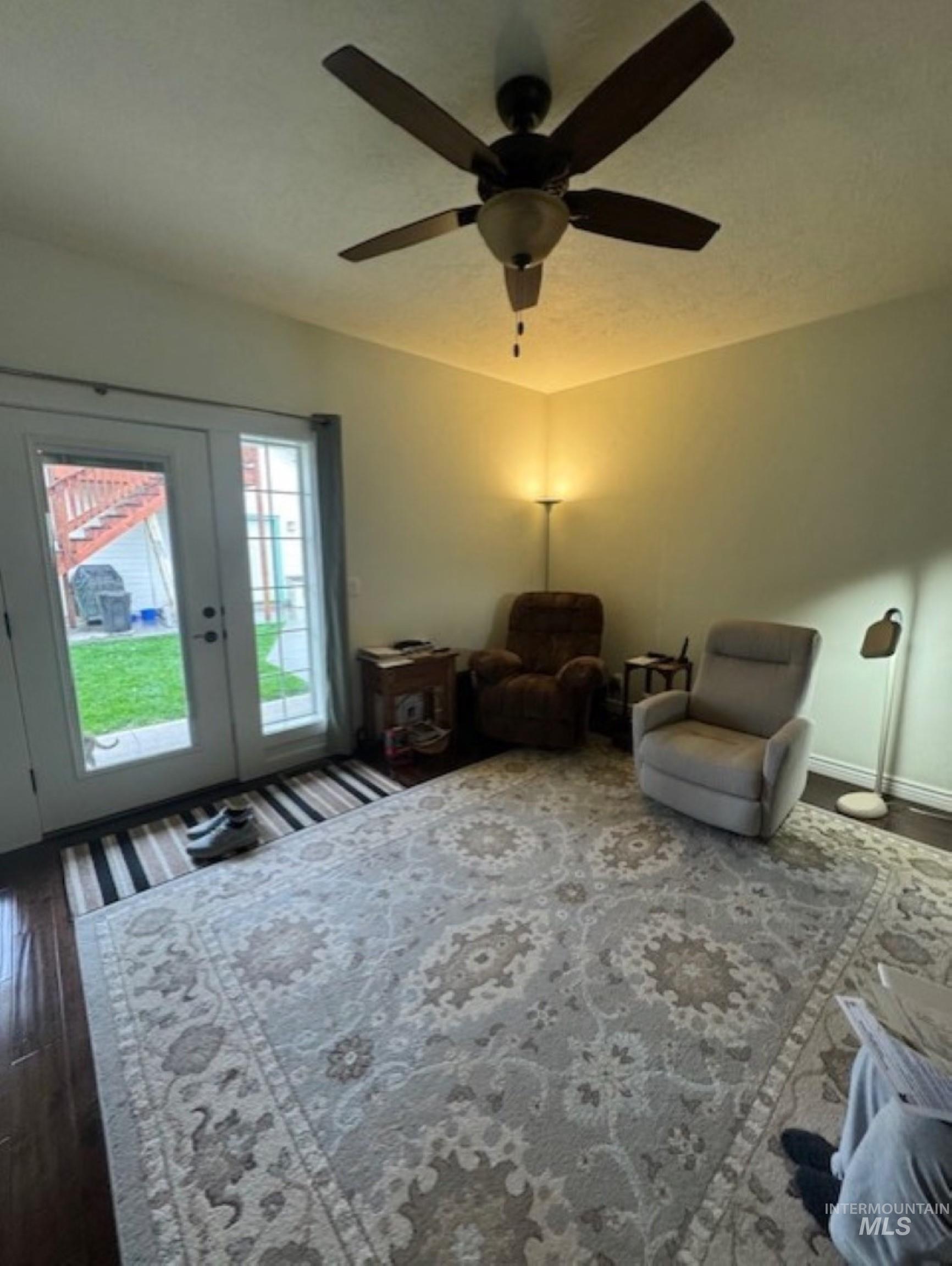 Living area with dark wood finished floors, a ceiling fan, and french doors