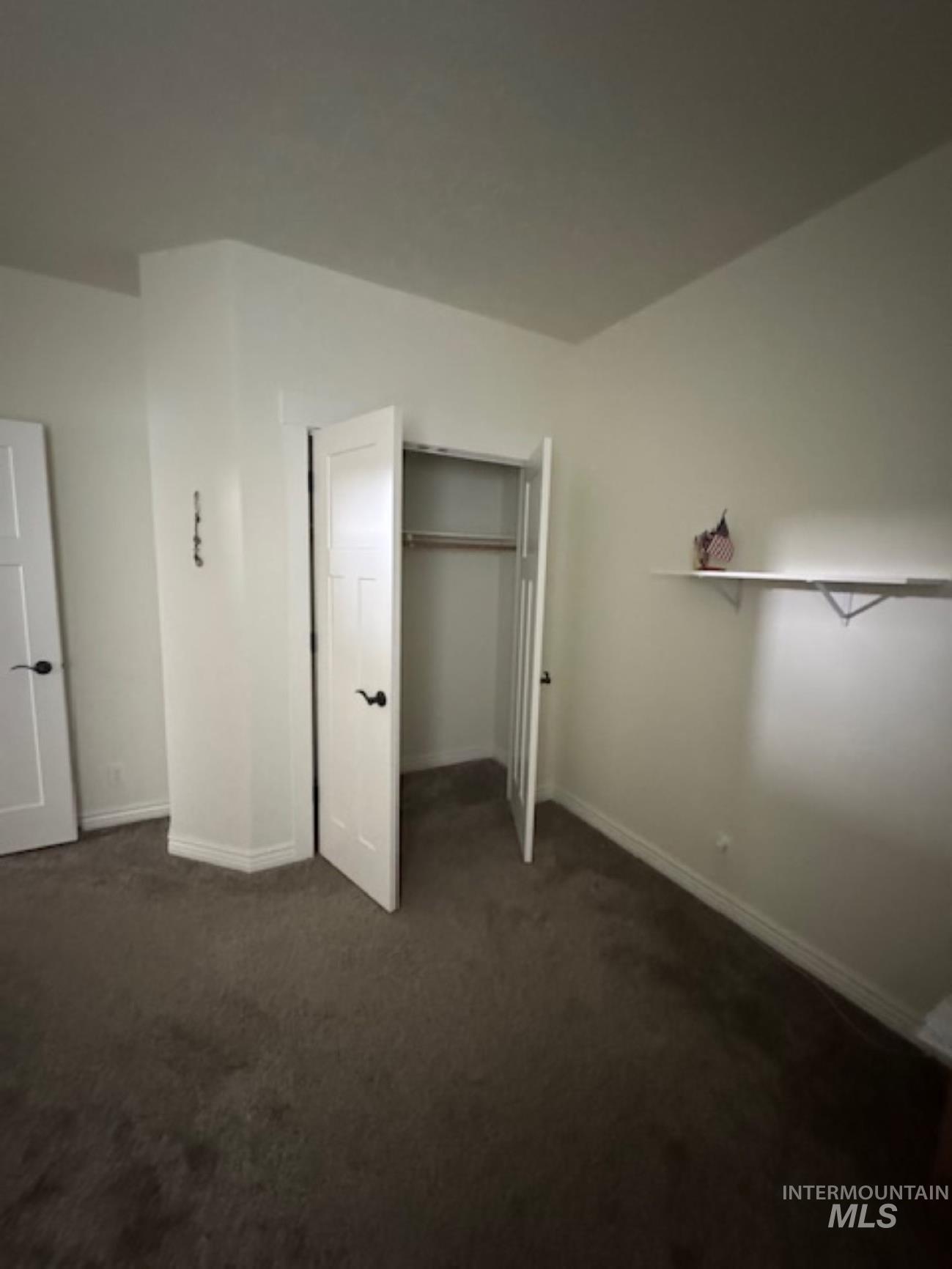 Unfurnished bedroom with dark carpet and a closet