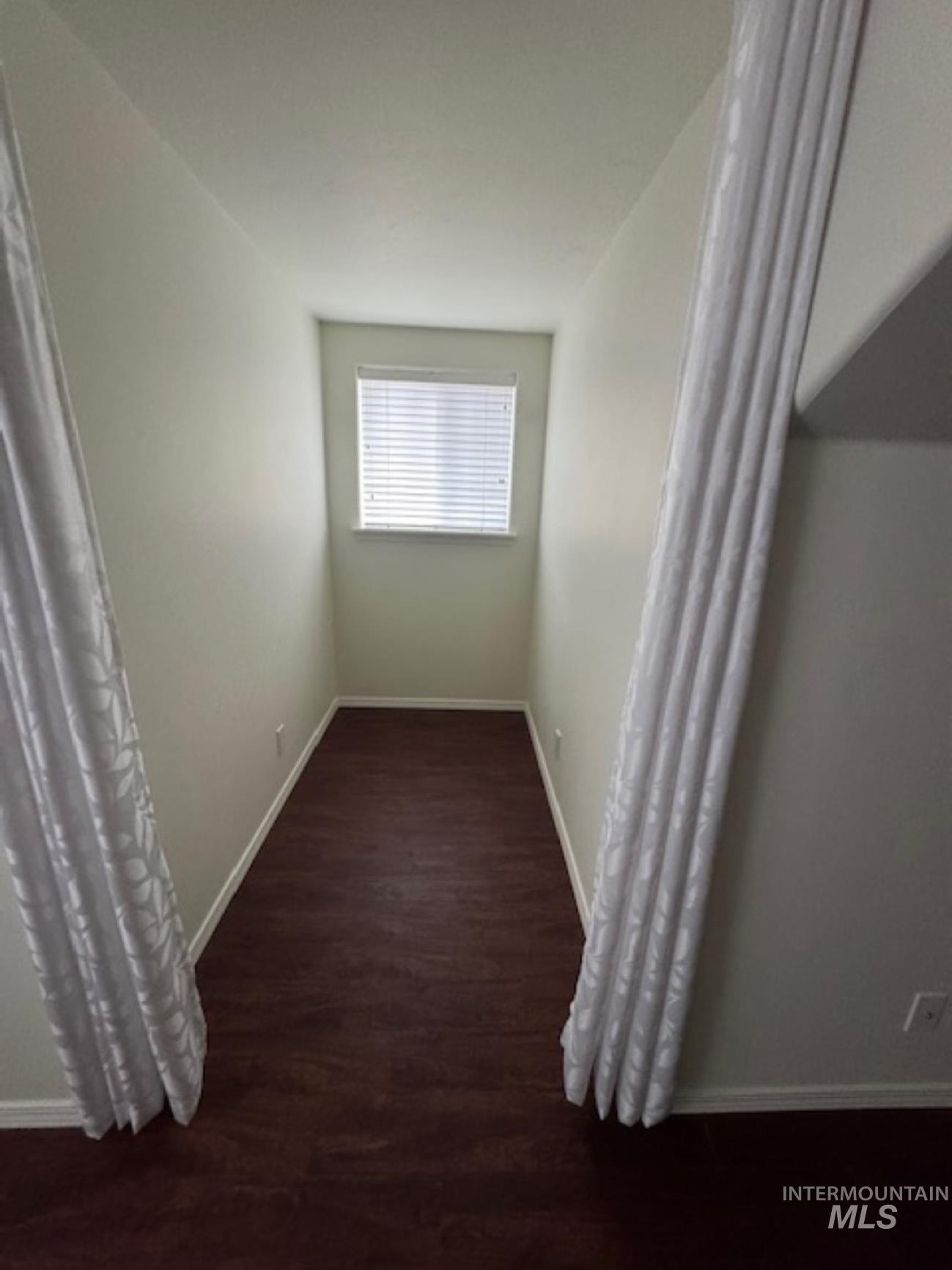 Corridor featuring baseboards and dark wood-style floors