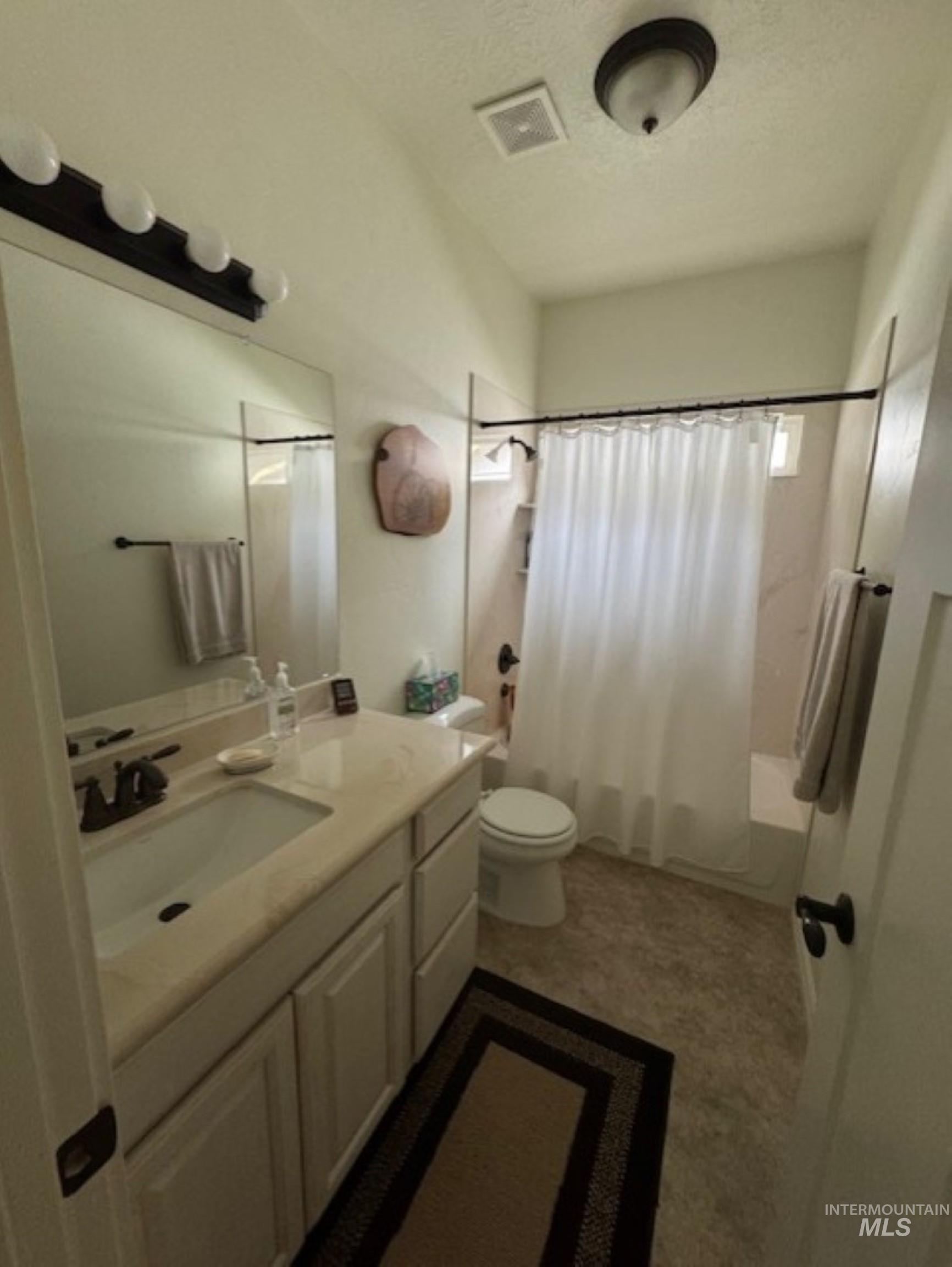 Bathroom featuring shower / bathtub combination with curtain, vanity, and a textured ceiling