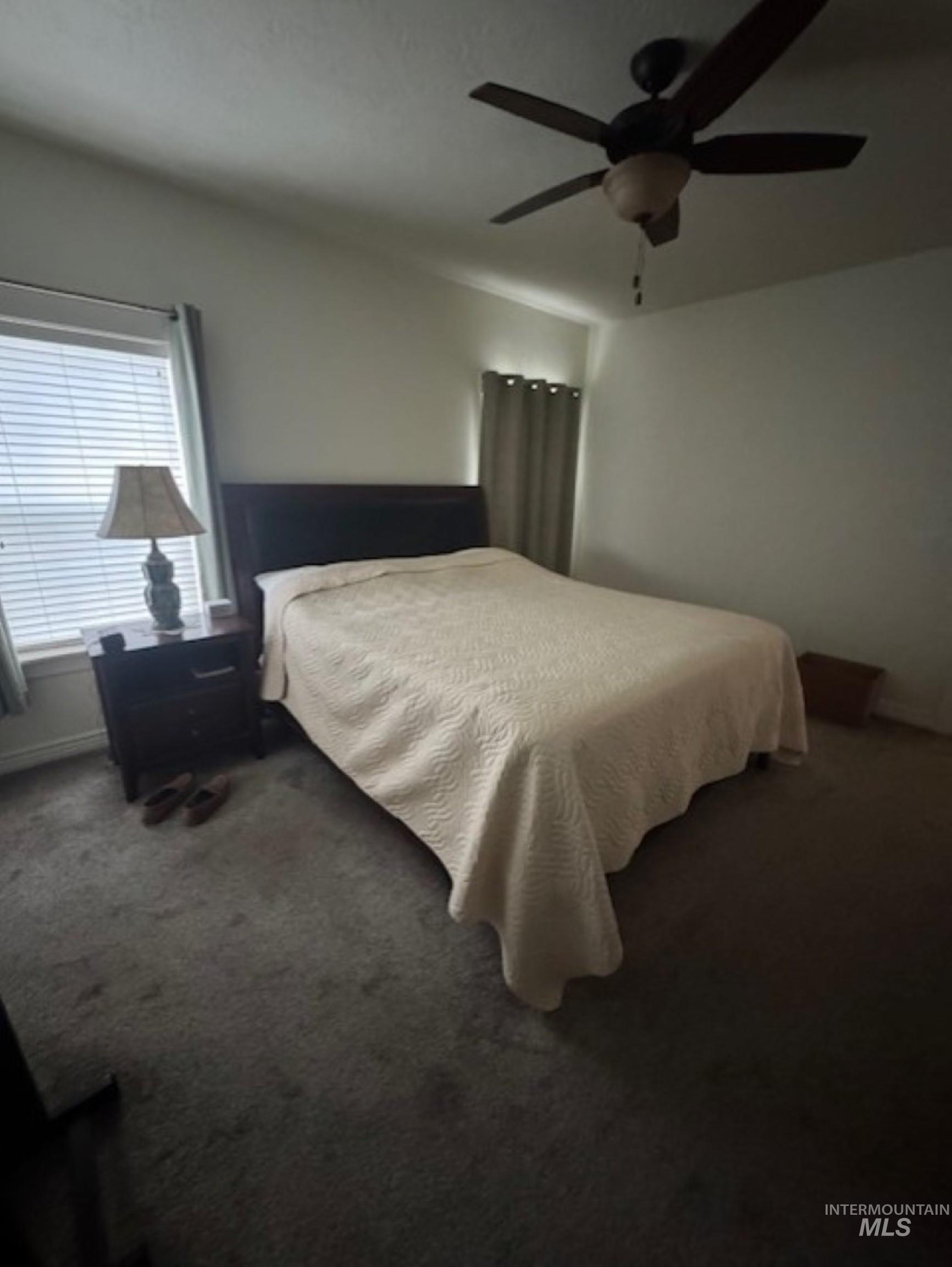 Bedroom with a ceiling fan and dark carpet