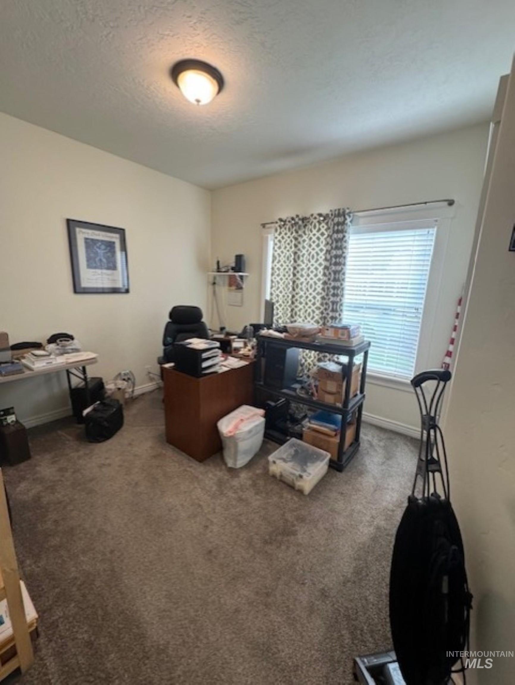 Office featuring dark colored carpet and a textured ceiling