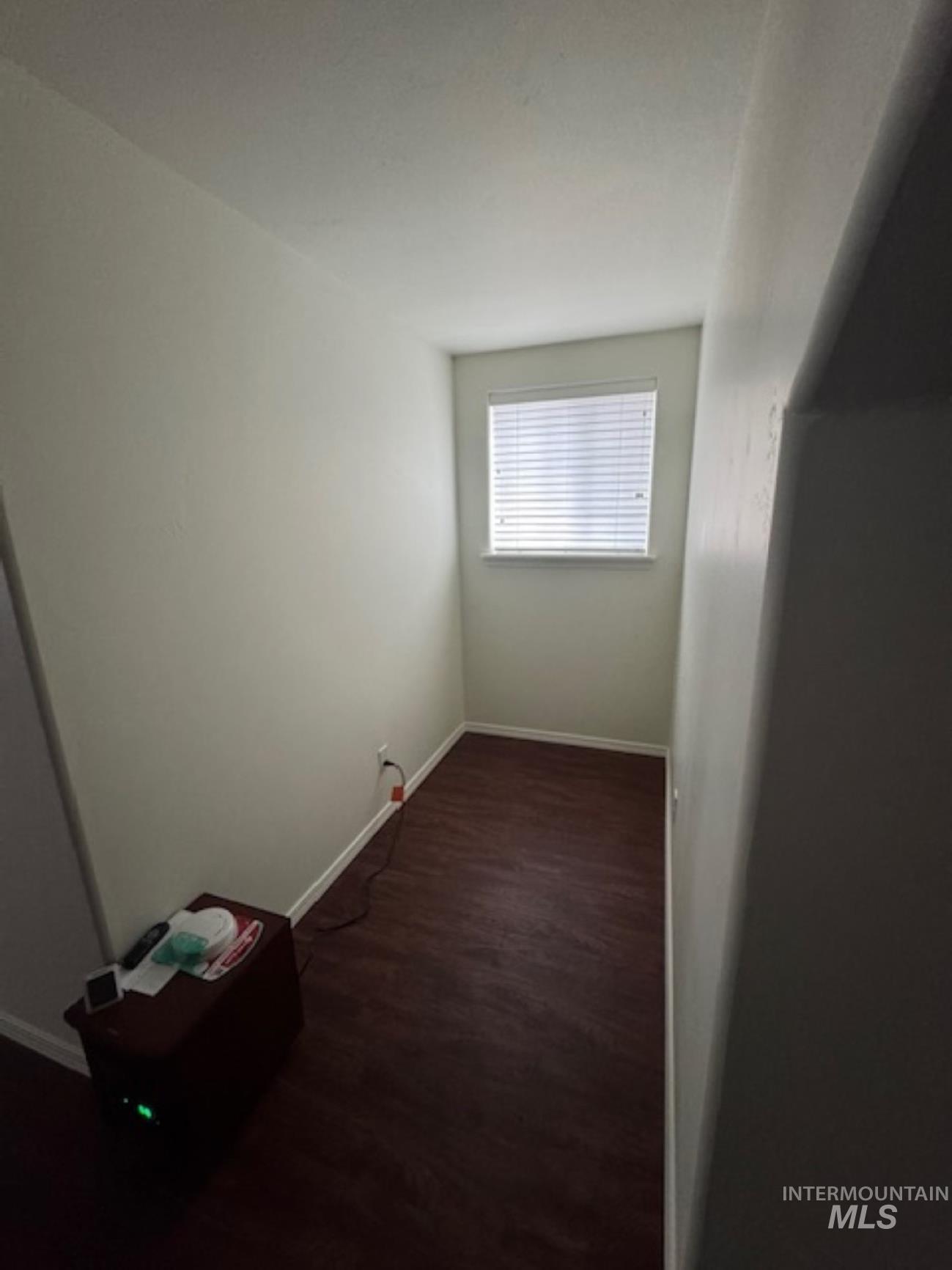 Unfurnished room with dark wood-style flooring and baseboards