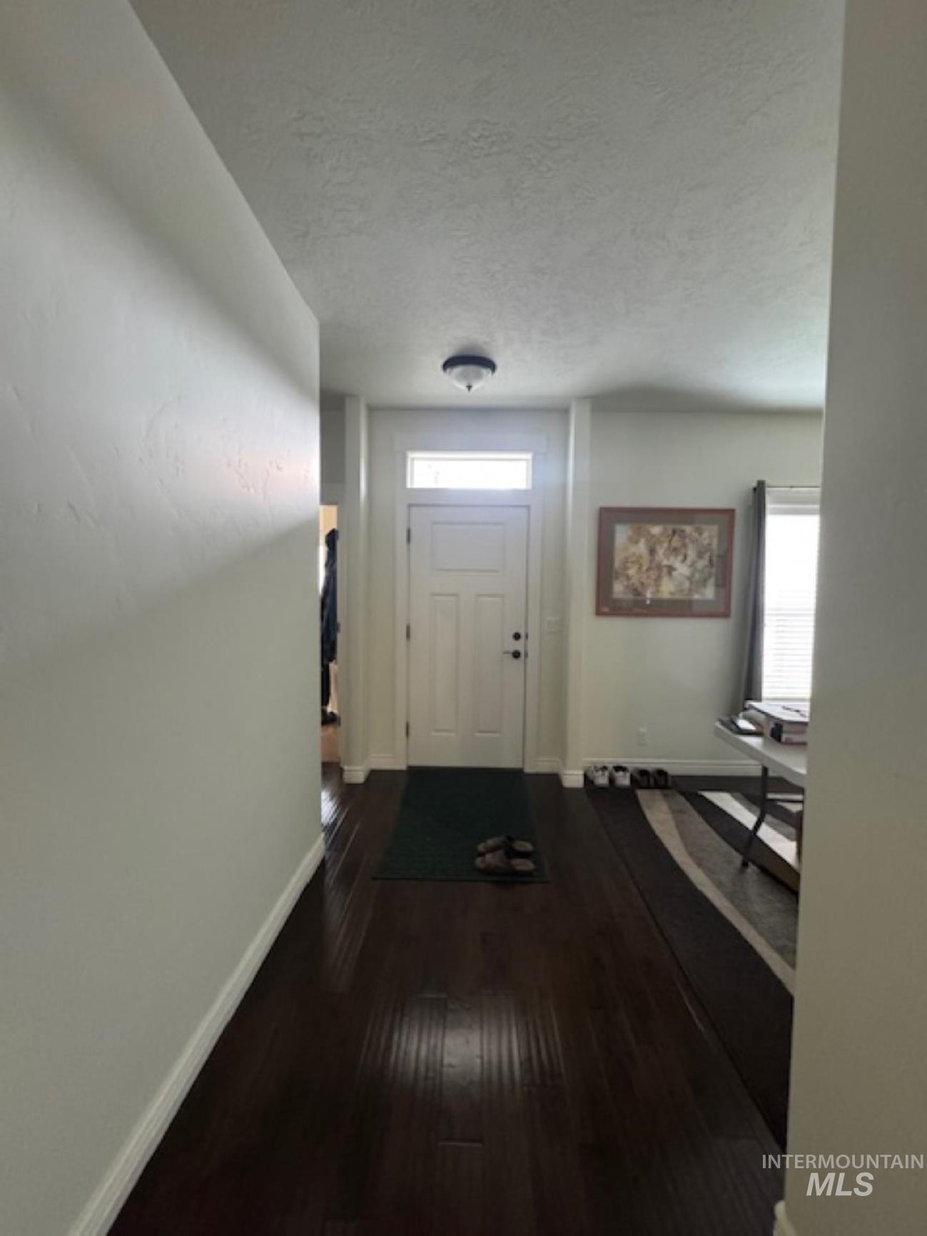 Doorway to outside featuring a textured ceiling and wood finished floors