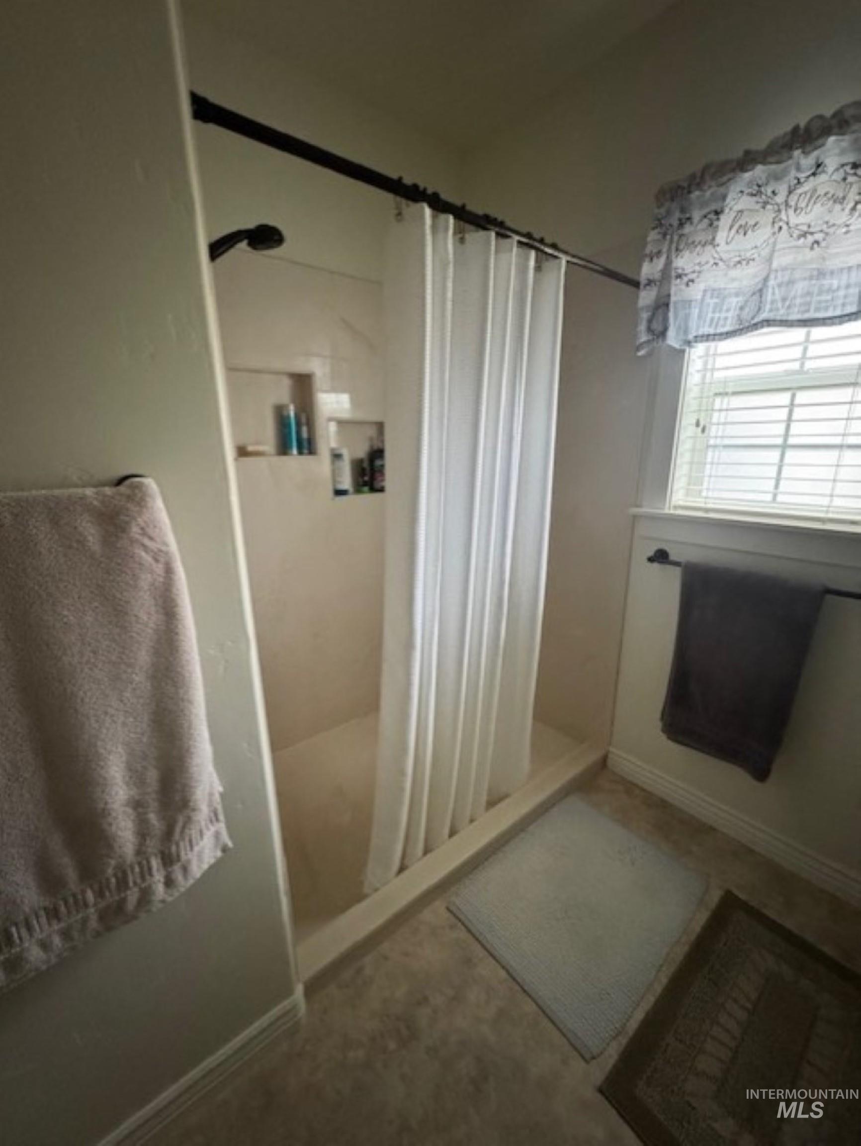 Bathroom featuring a shower with shower curtain and baseboards