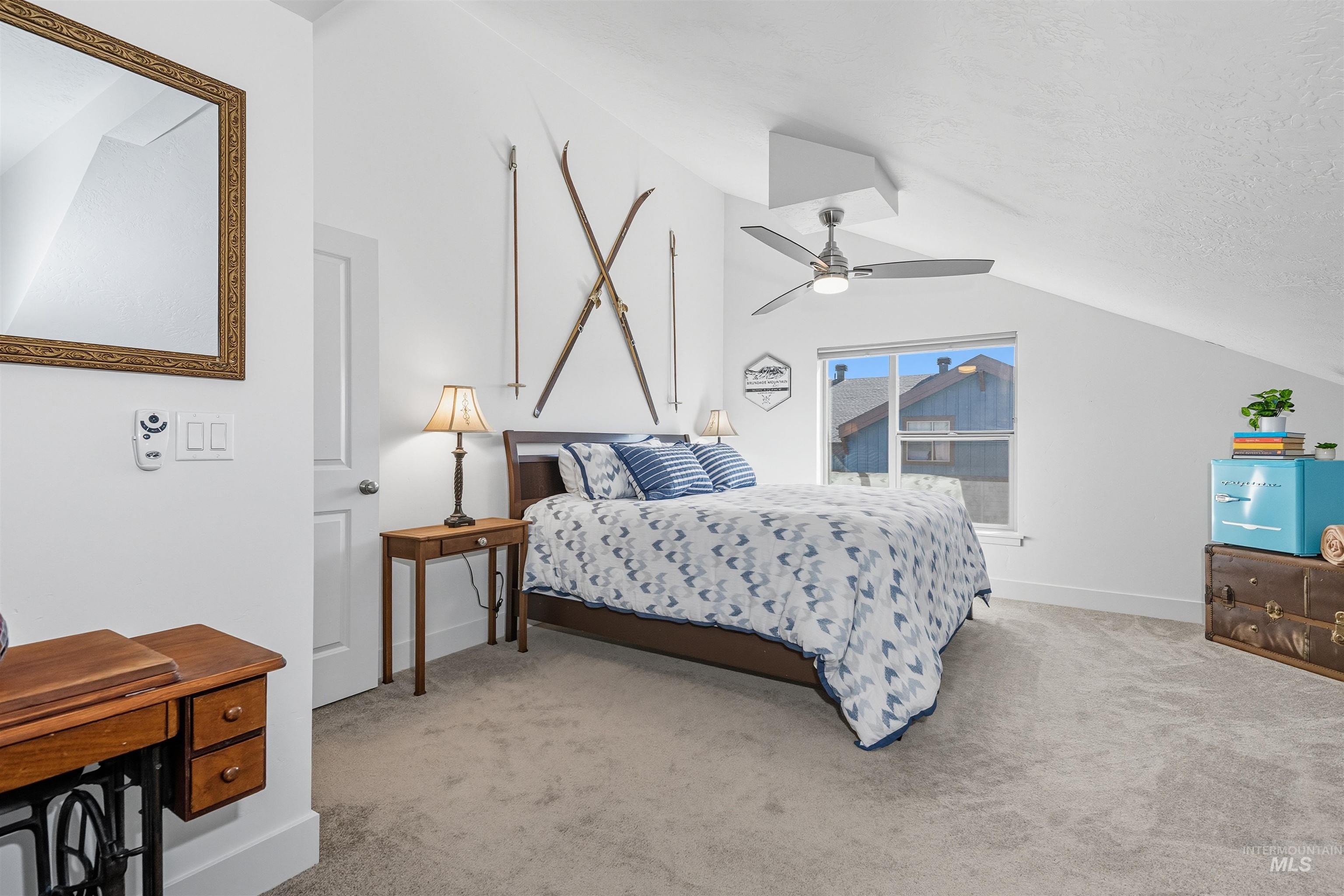 Bedroom featuring light colored carpet, vaulted ceiling, a ceiling fan, and a textured ceiling
