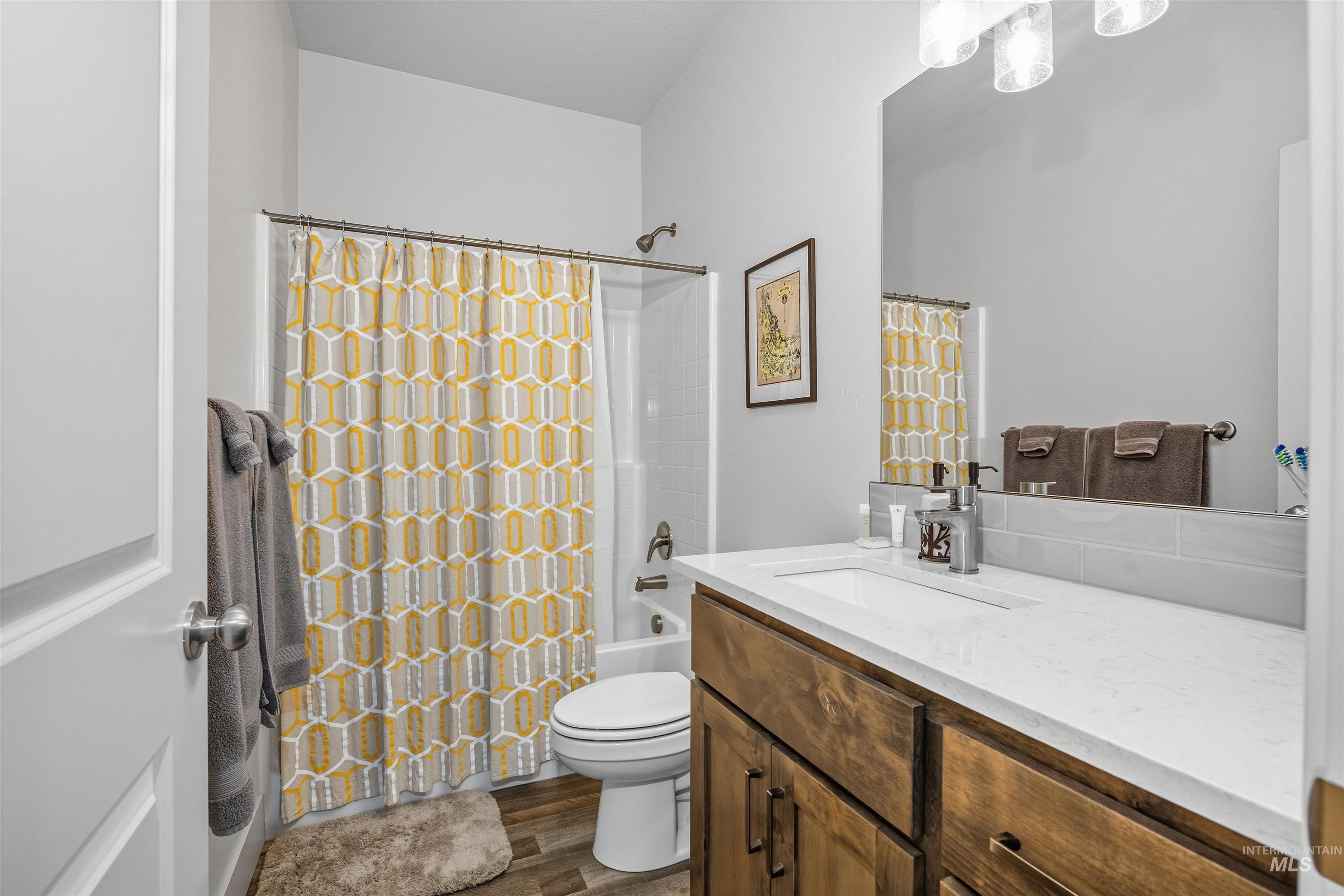 Full bathroom with shower / tub combo with curtain, vanity, and dark wood finished floors