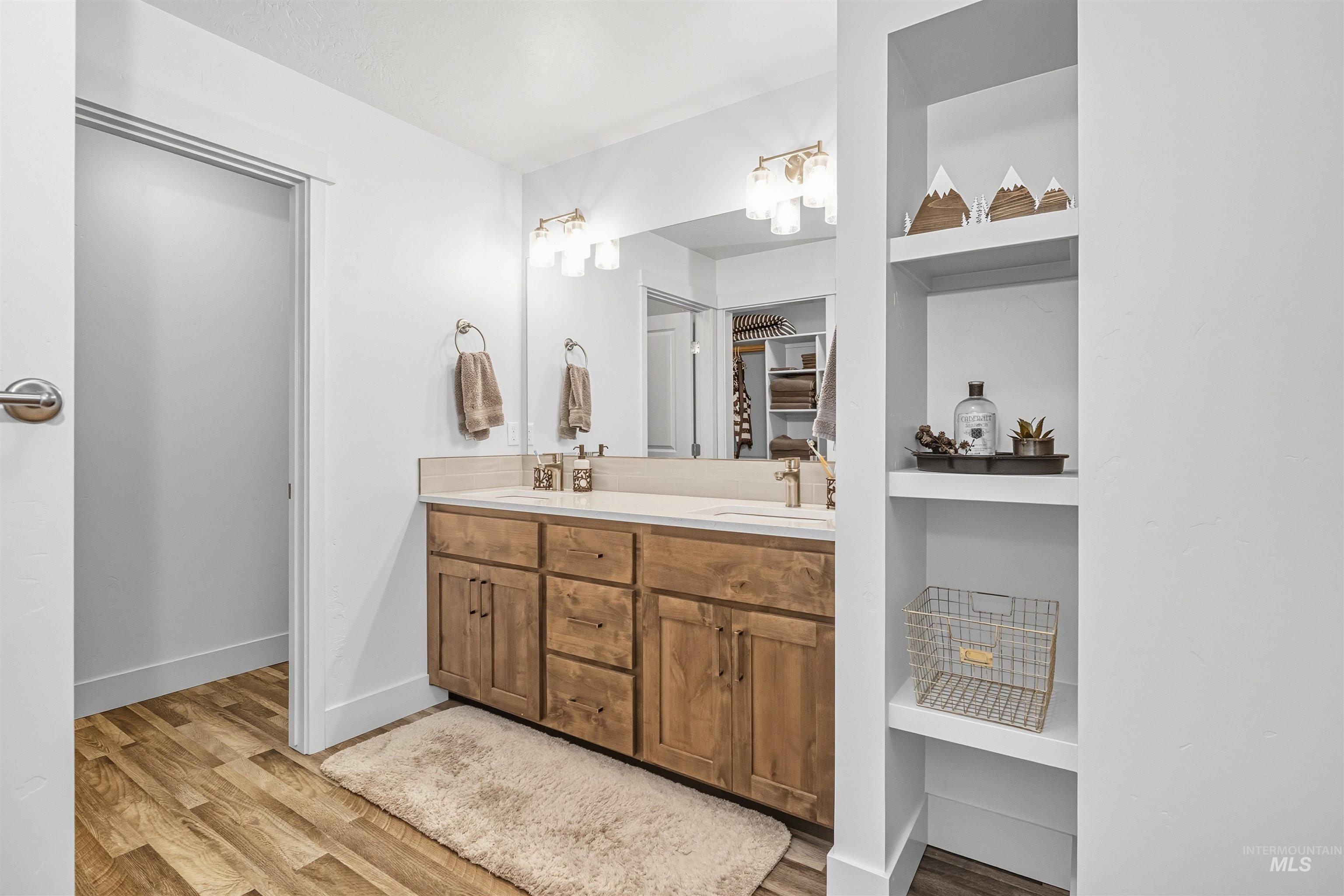 Bathroom with double vanity and light wood-style flooring