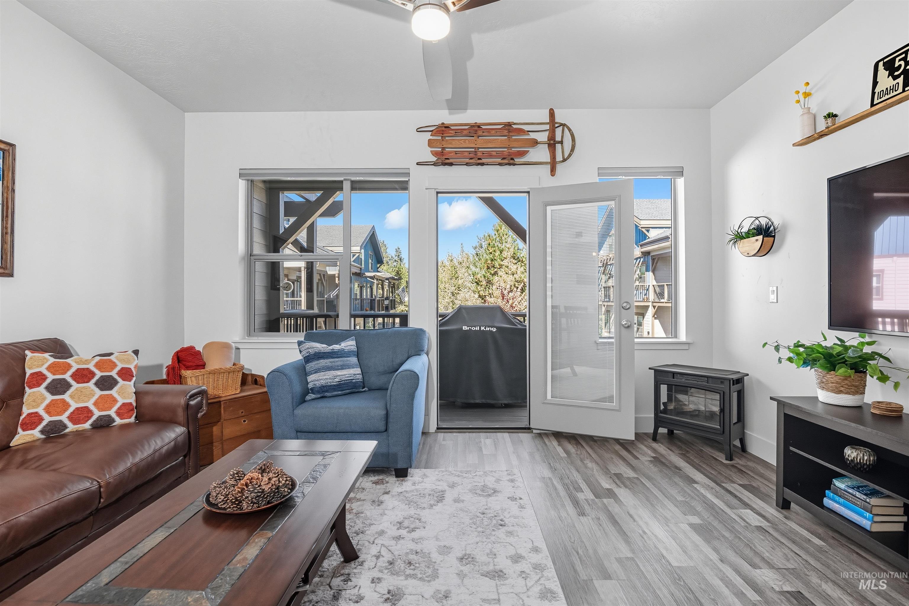 Living room featuring wood finished floors, a ceiling fan, and a wood stove