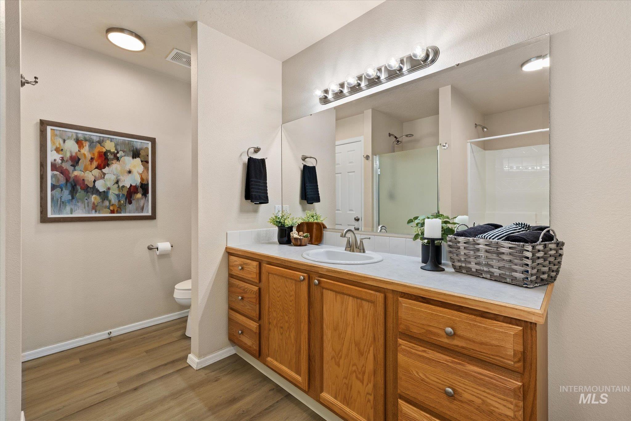 Bathroom featuring a stall shower, vanity, and light wood finished floors