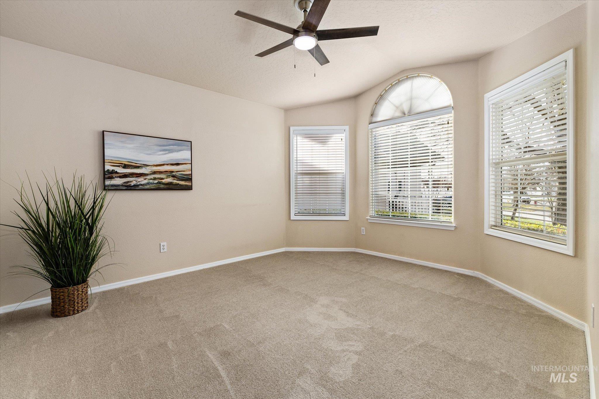 Carpeted empty room with vaulted ceiling and ceiling fan