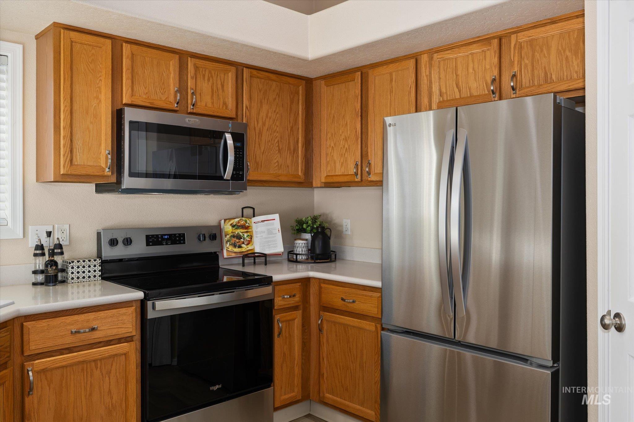 Kitchen with stainless steel appliances, brown cabinets, and light countertops