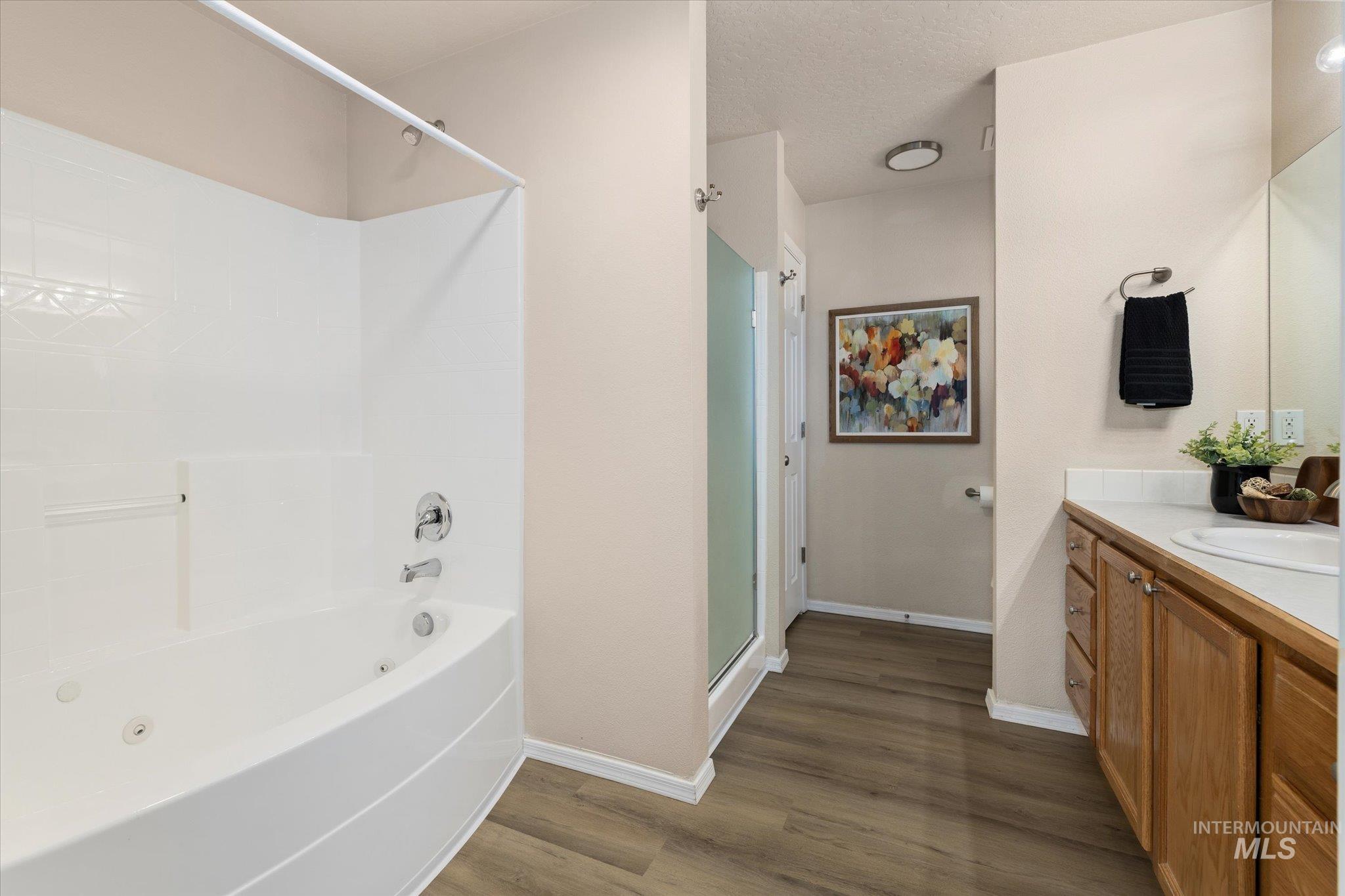 Full bath featuring vanity, dark wood finished floors, a textured ceiling, and shower / bath combination with glass door