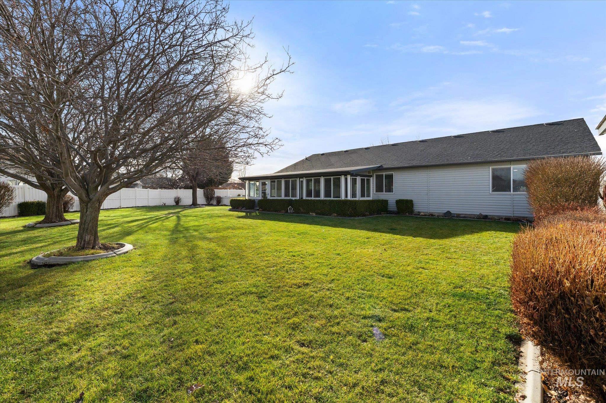 View of side of property with a sunroom, a fenced backyard, and a shingled roof