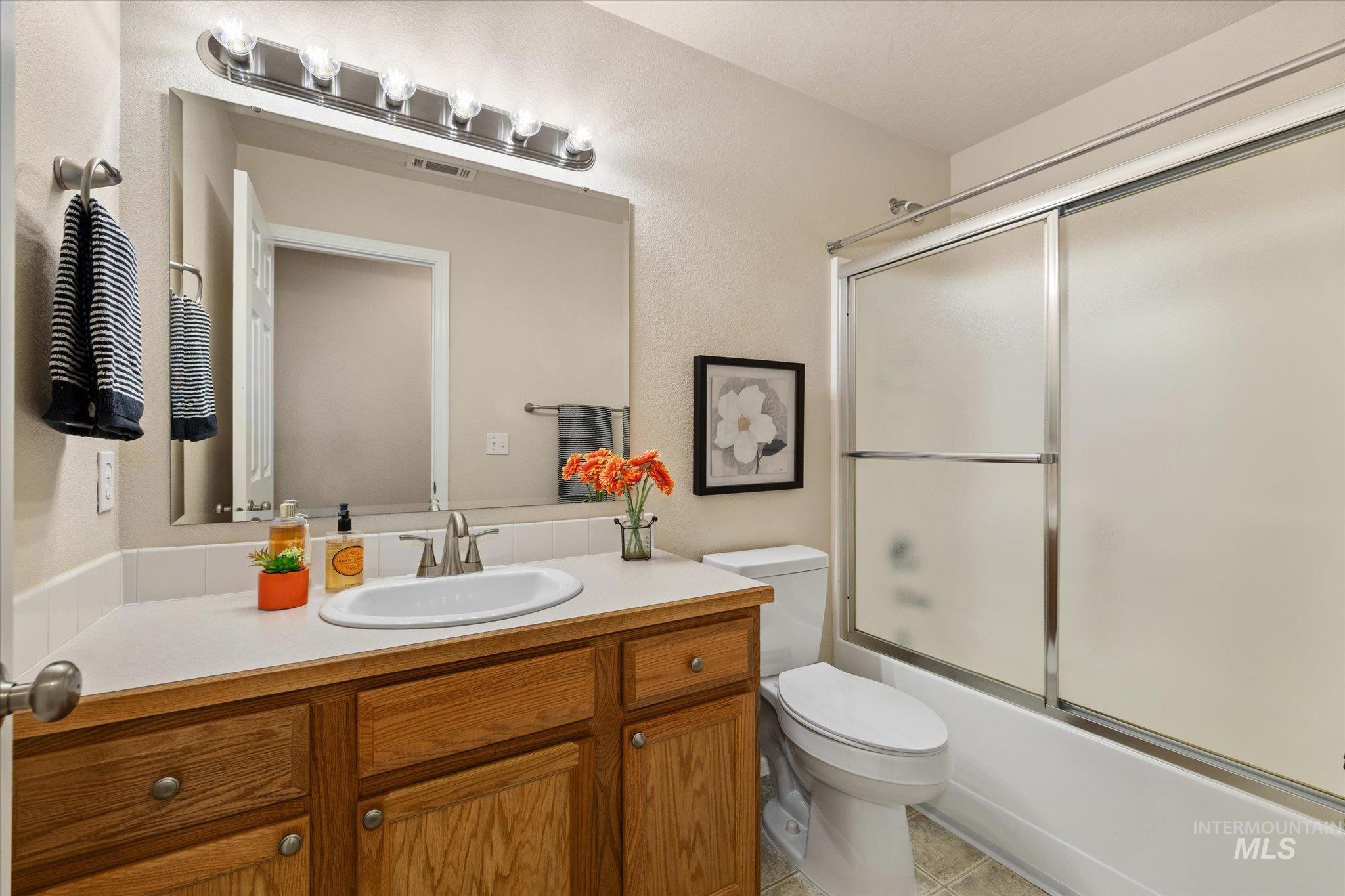 Full bathroom featuring vanity, enclosed tub / shower combo, and light tile patterned flooring