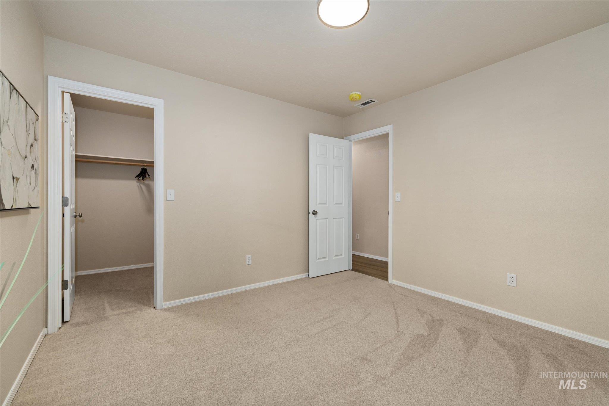 Unfurnished bedroom with a spacious closet and light carpet