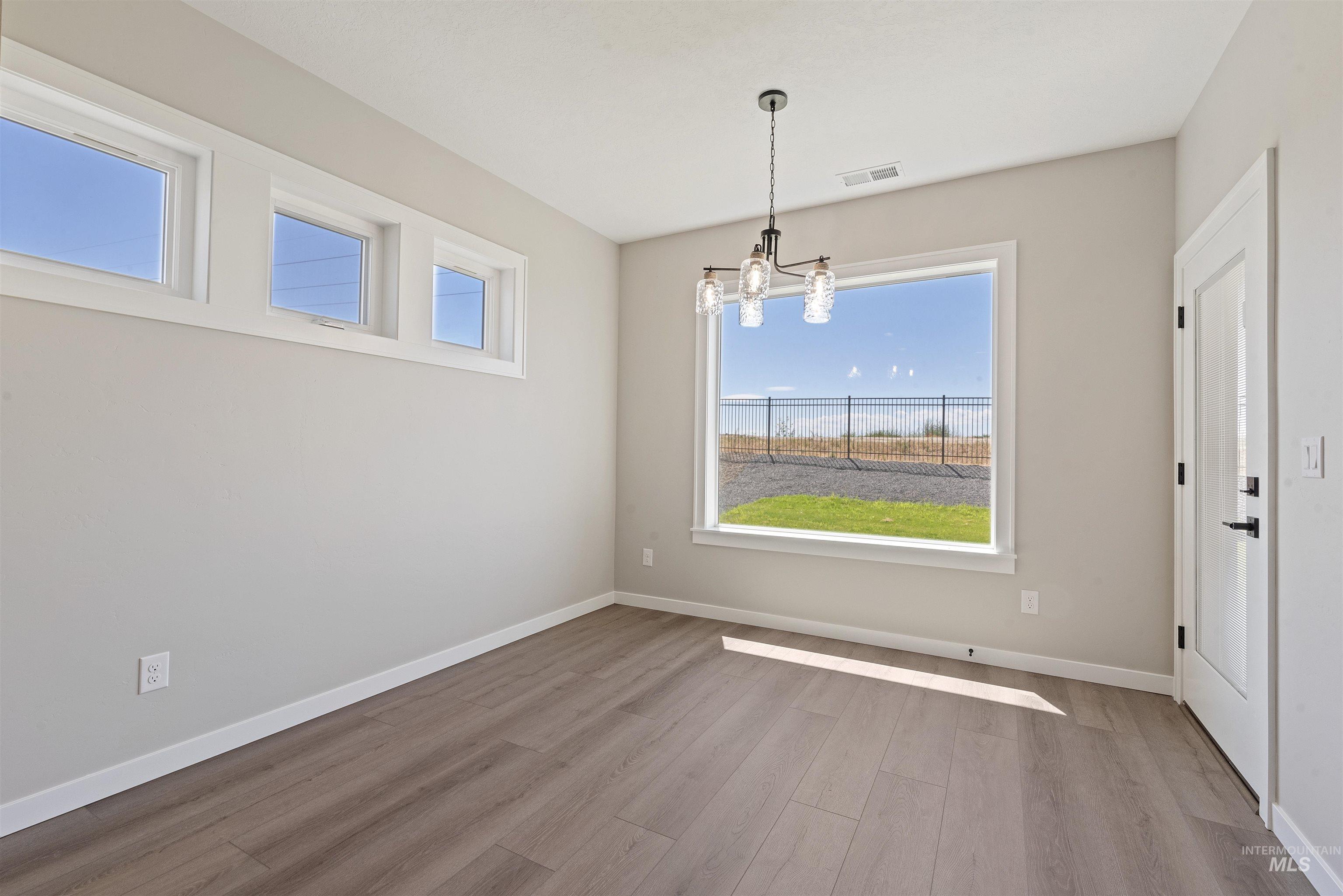 Unfurnished dining area featuring wood finished floors and a chandelier
