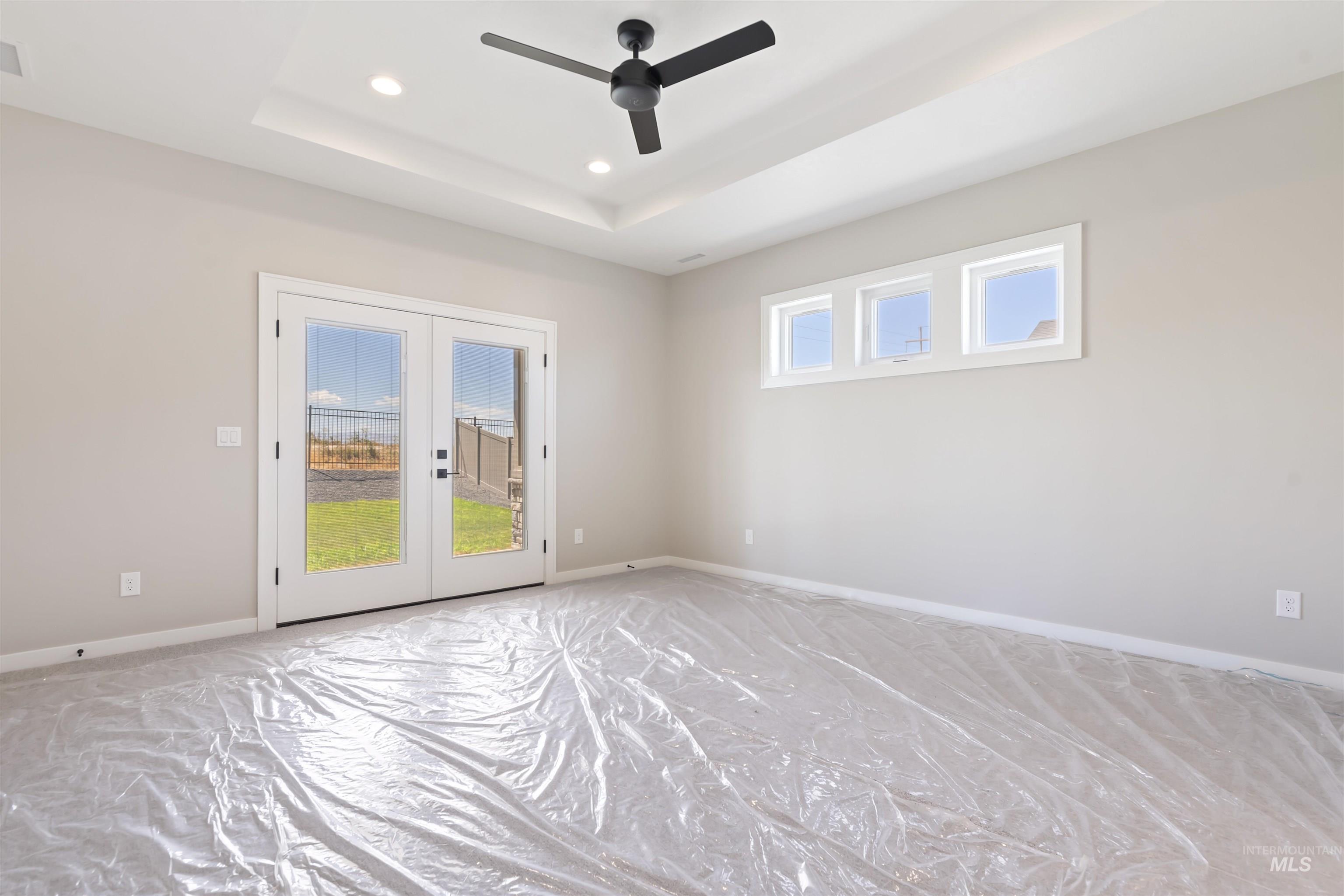 master bedroom with French doors, a raised ceiling, recessed lighting, and ceiling fan