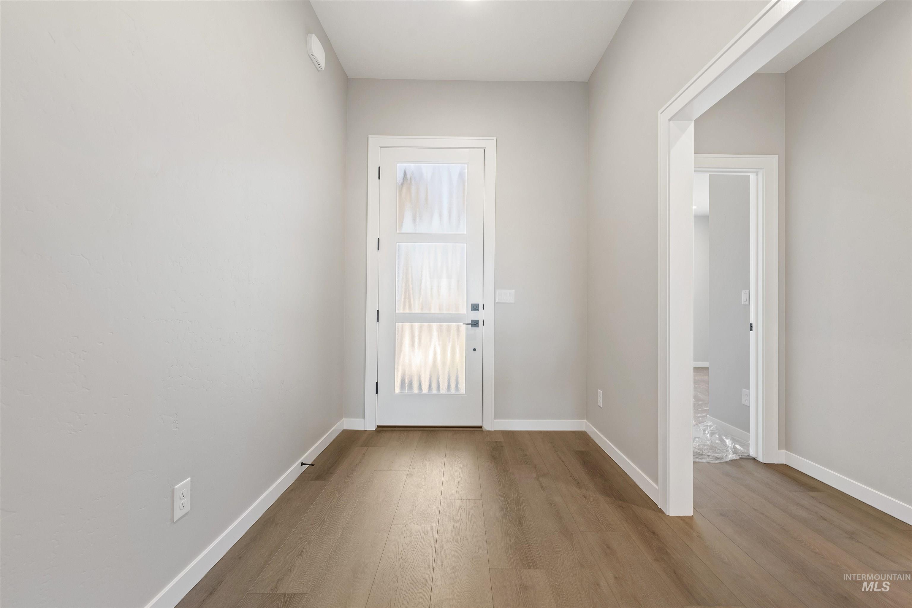 Doorway to outside featuring wood finished floors and baseboards