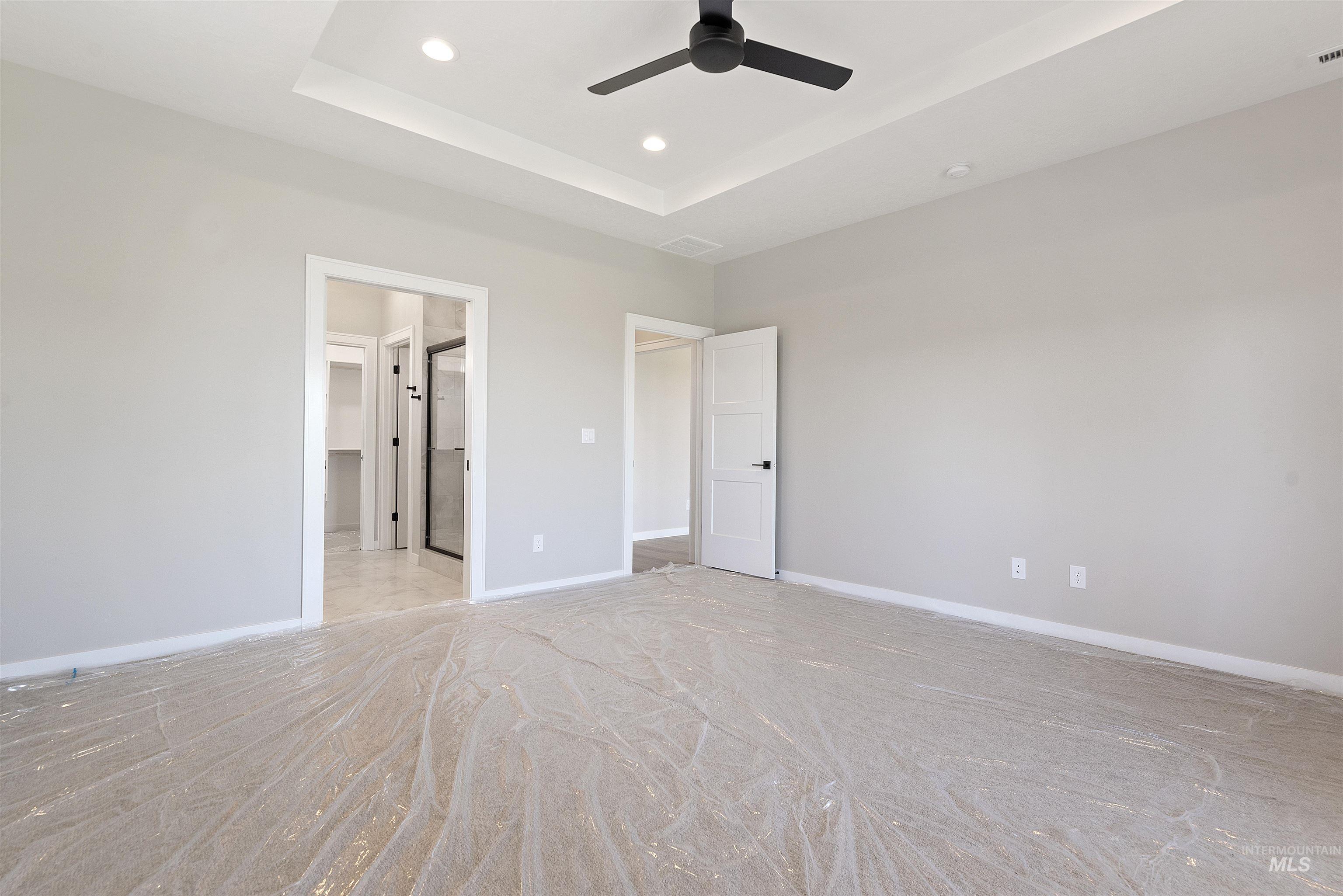 Unfurnished bedroom with a raised ceiling, recessed lighting, and a ceiling fan