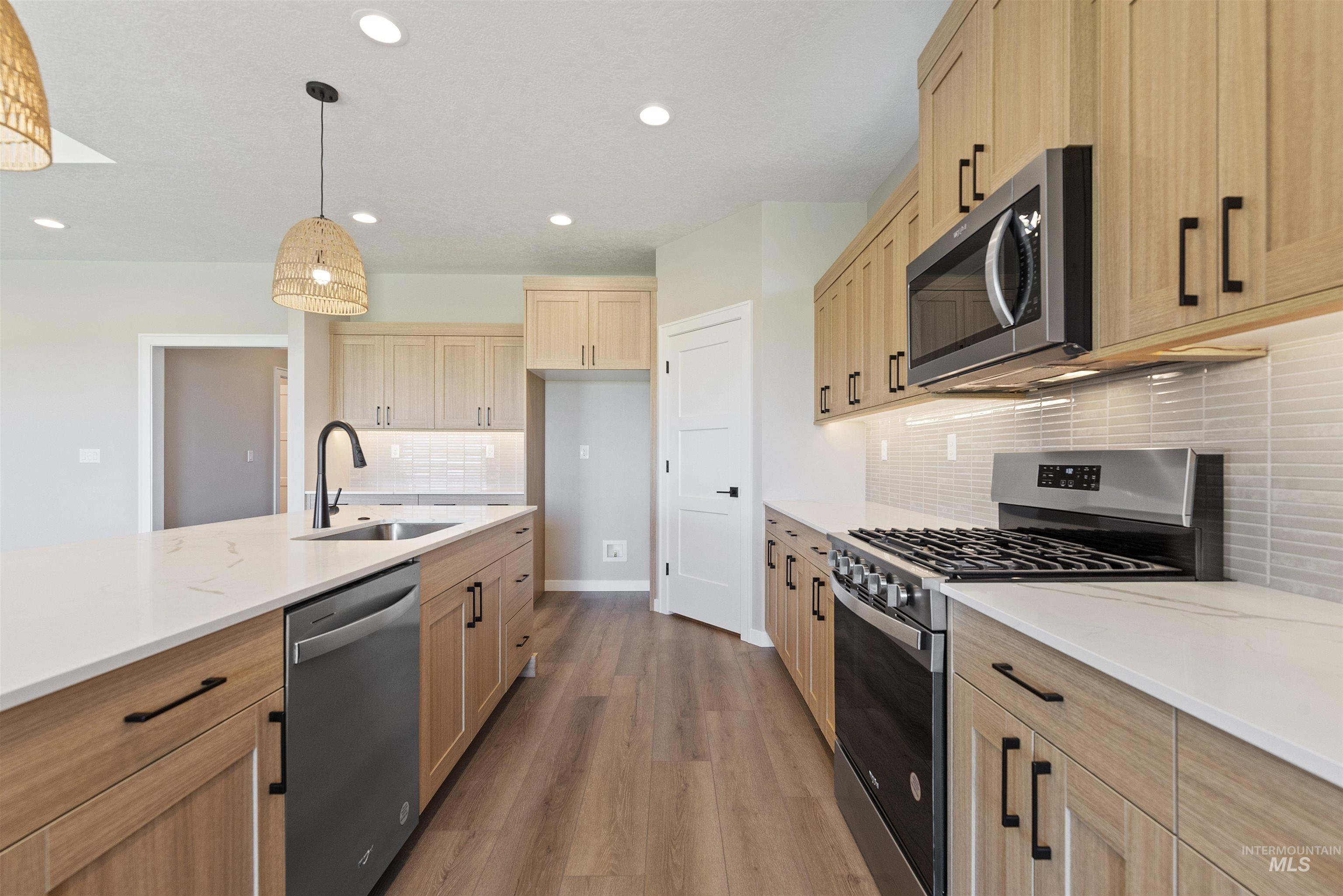 Kitchen featuring stainless steel appliances, wood finished floors, decorative backsplash, recessed lighting, and light brown cabinets