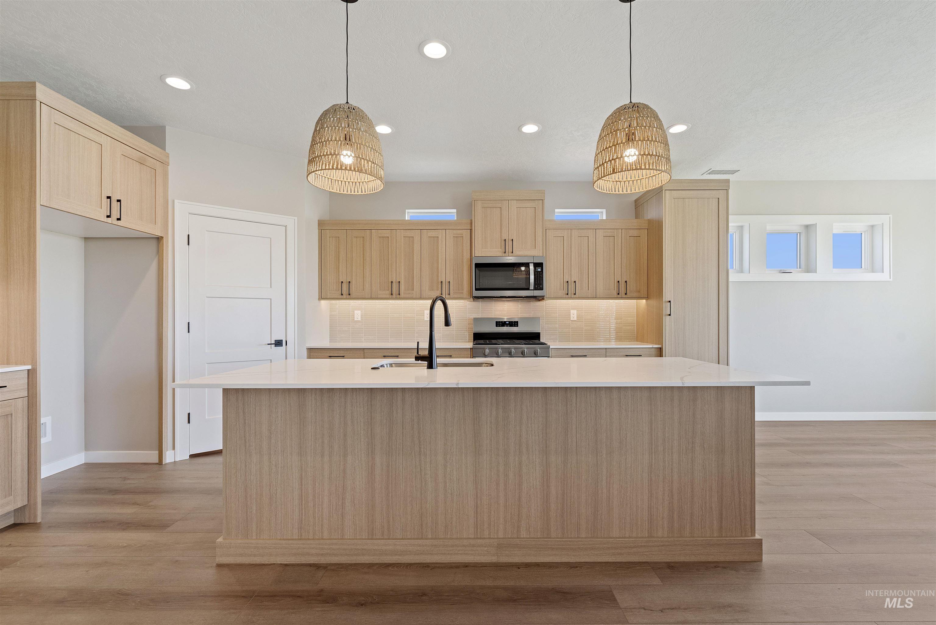 Kitchen featuring light brown cabinets, light countertops, appliances with stainless steel finishes, and recessed lighting