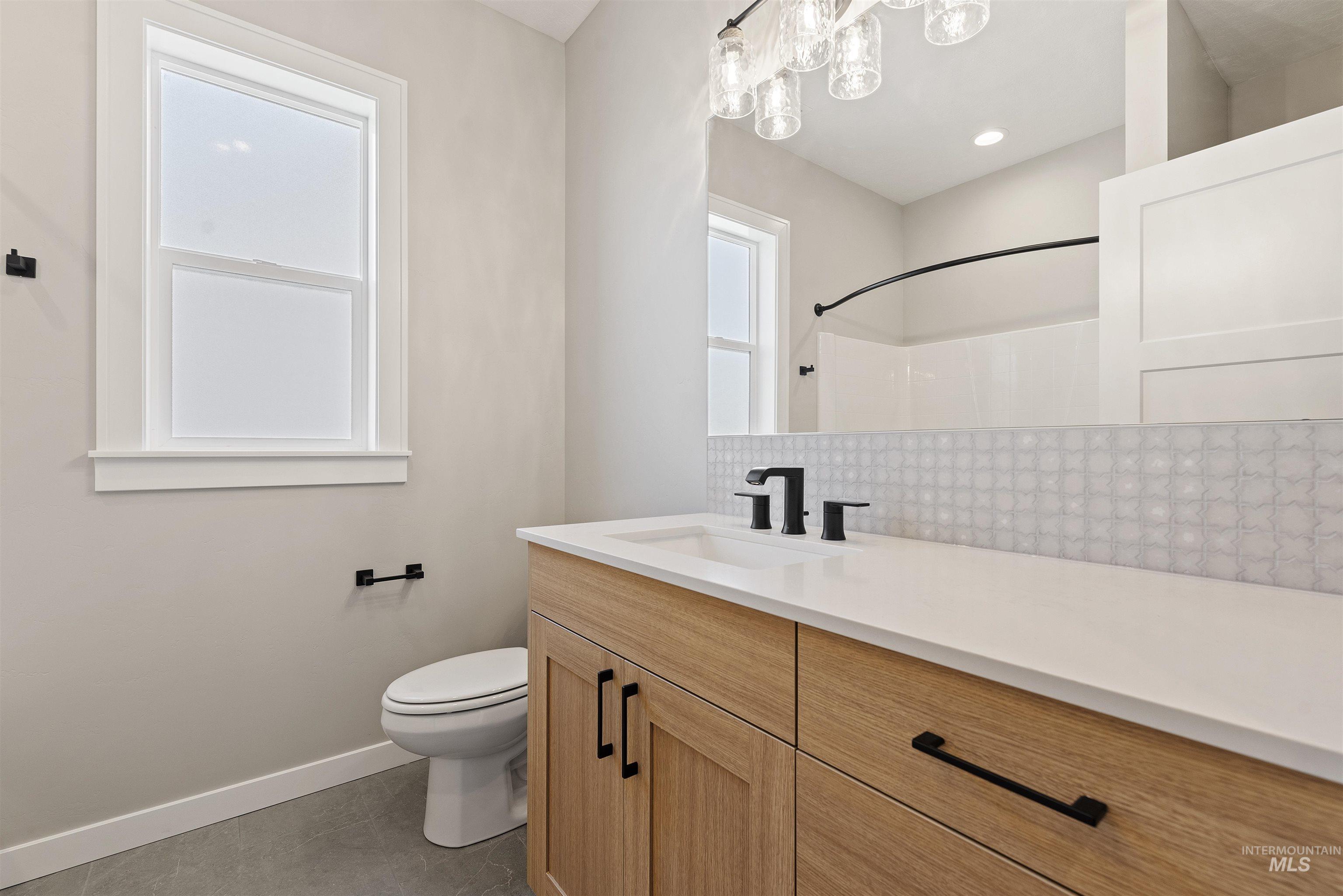Full bath featuring backsplash, vanity, a shower, and tile patterned flooring